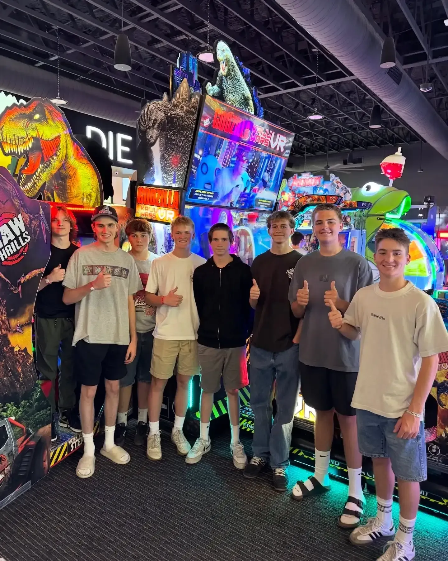 Group of people posing at a colorful arcade with bright neon game machines and displays