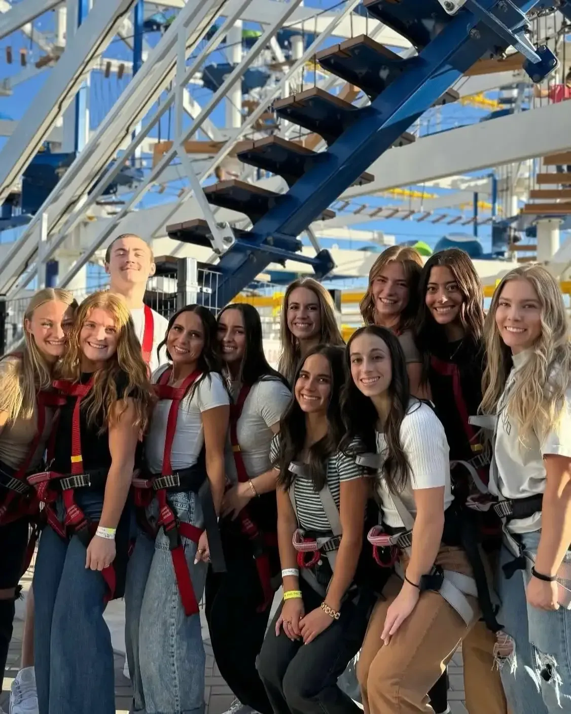 Group of people posing under the ropes course, smiling at the camera.