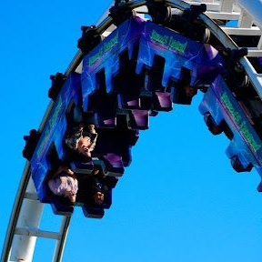 Blue roller coaster car upside down on a loop against a clear sky