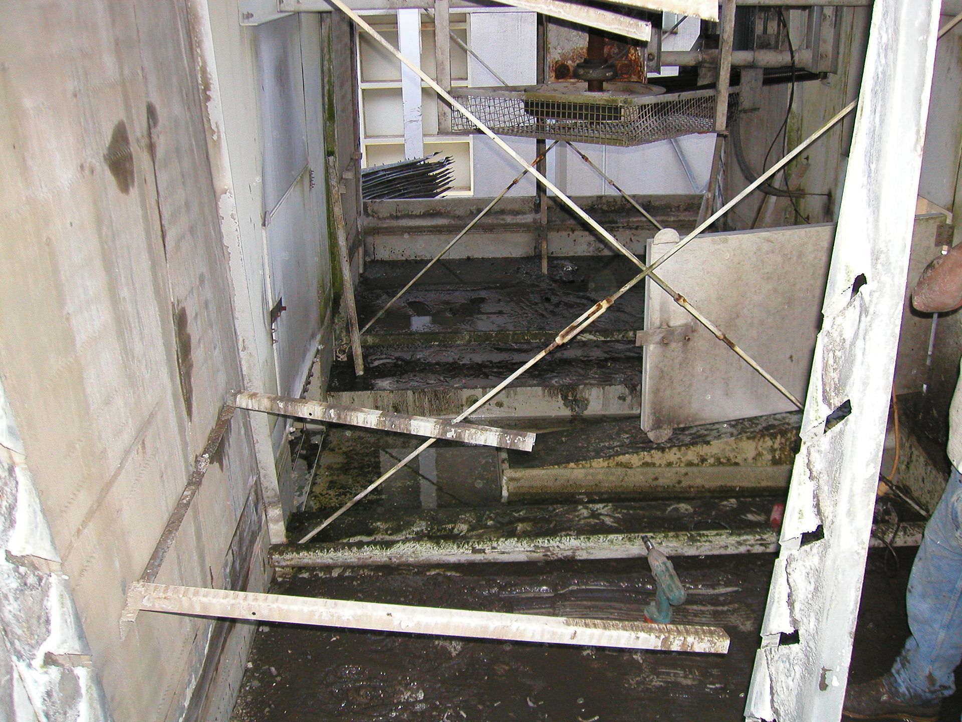 Dilapidated stairwell blocked by a metal barrier, with worn steps and peeling walls.