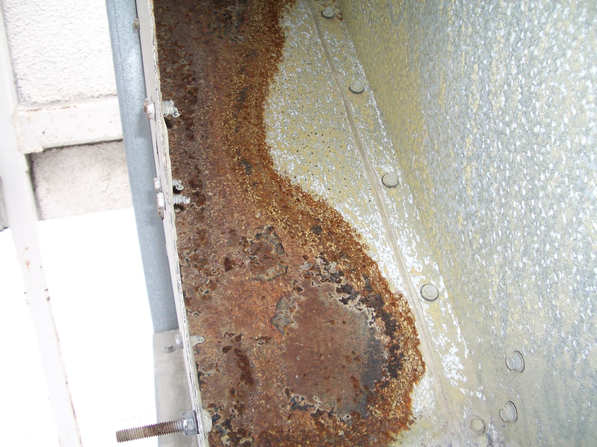 Close-up of a rusted, corroded metal surface with peeling paint and water droplets