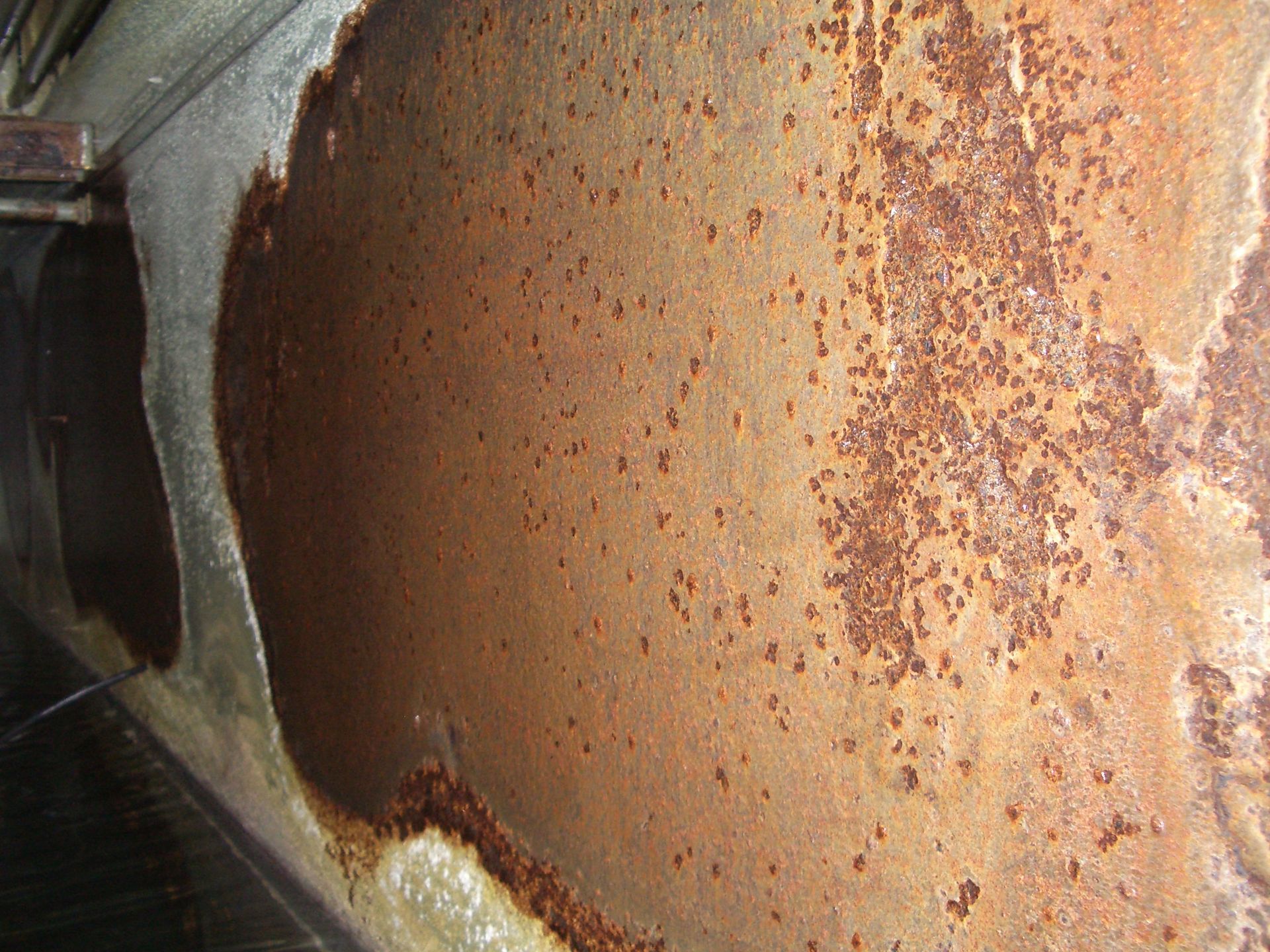 Close-up of a rusted metal surface with orange-brown corrosion and peeling paint.