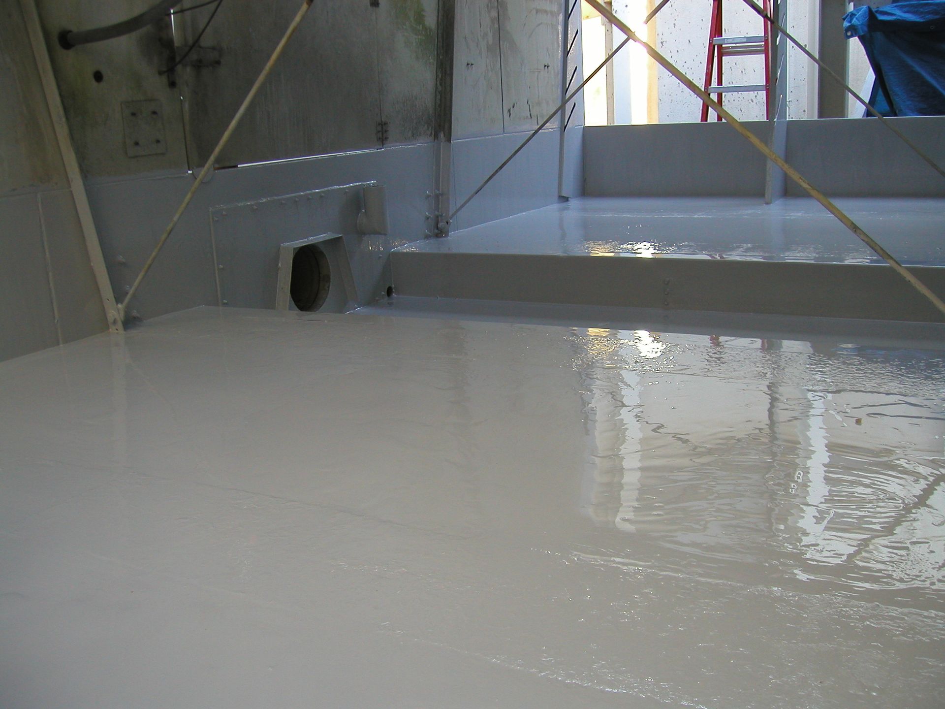 White-coated industrial floor with wet sheen inside a building under construction