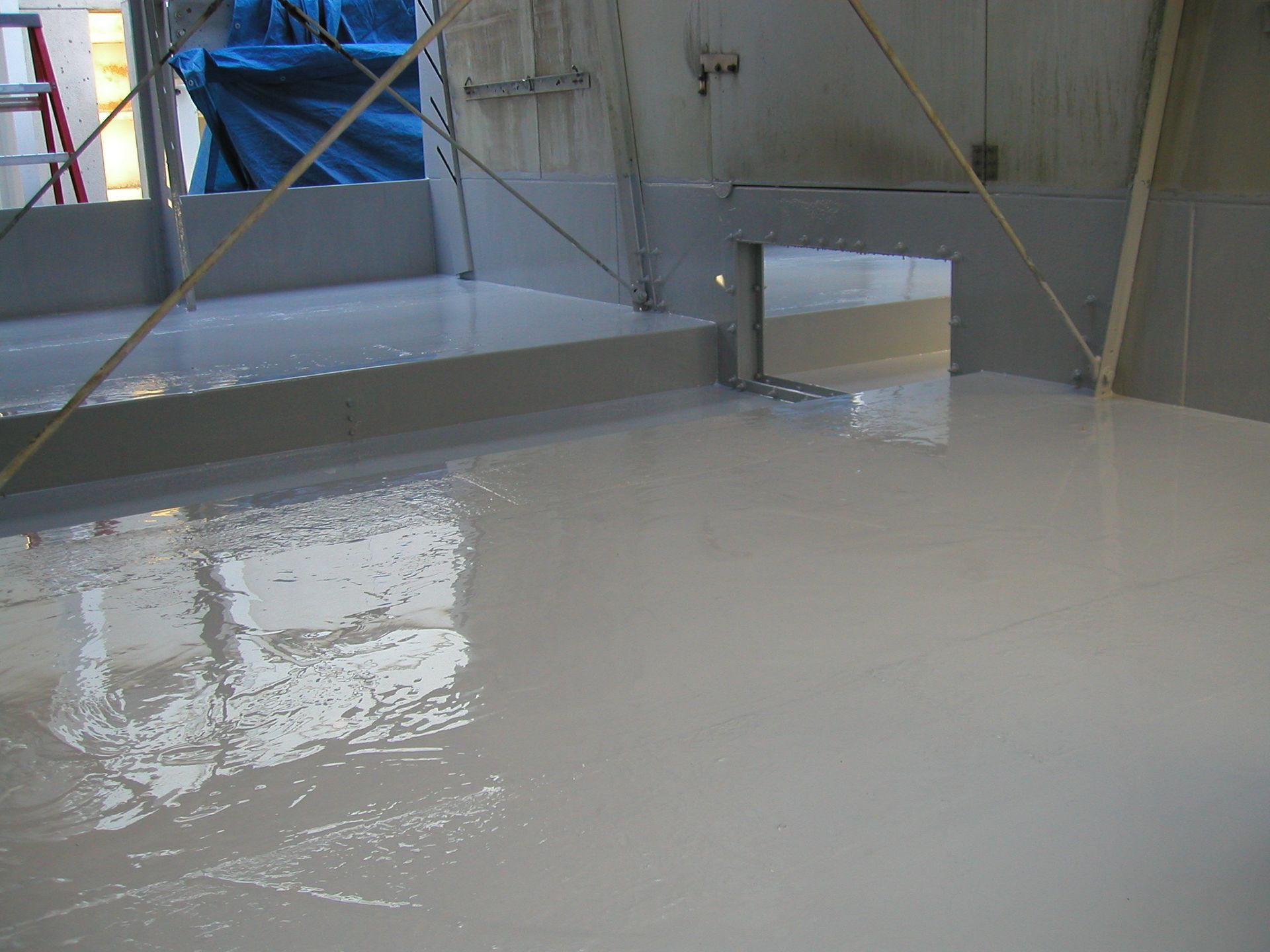 Gray industrial room with a large pool of white liquid covering the floor