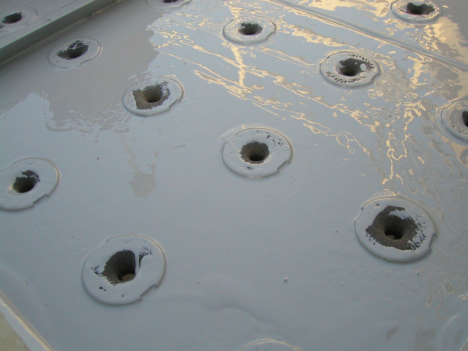 Gray metal surface with multiple circular holes and yellow scuff marks