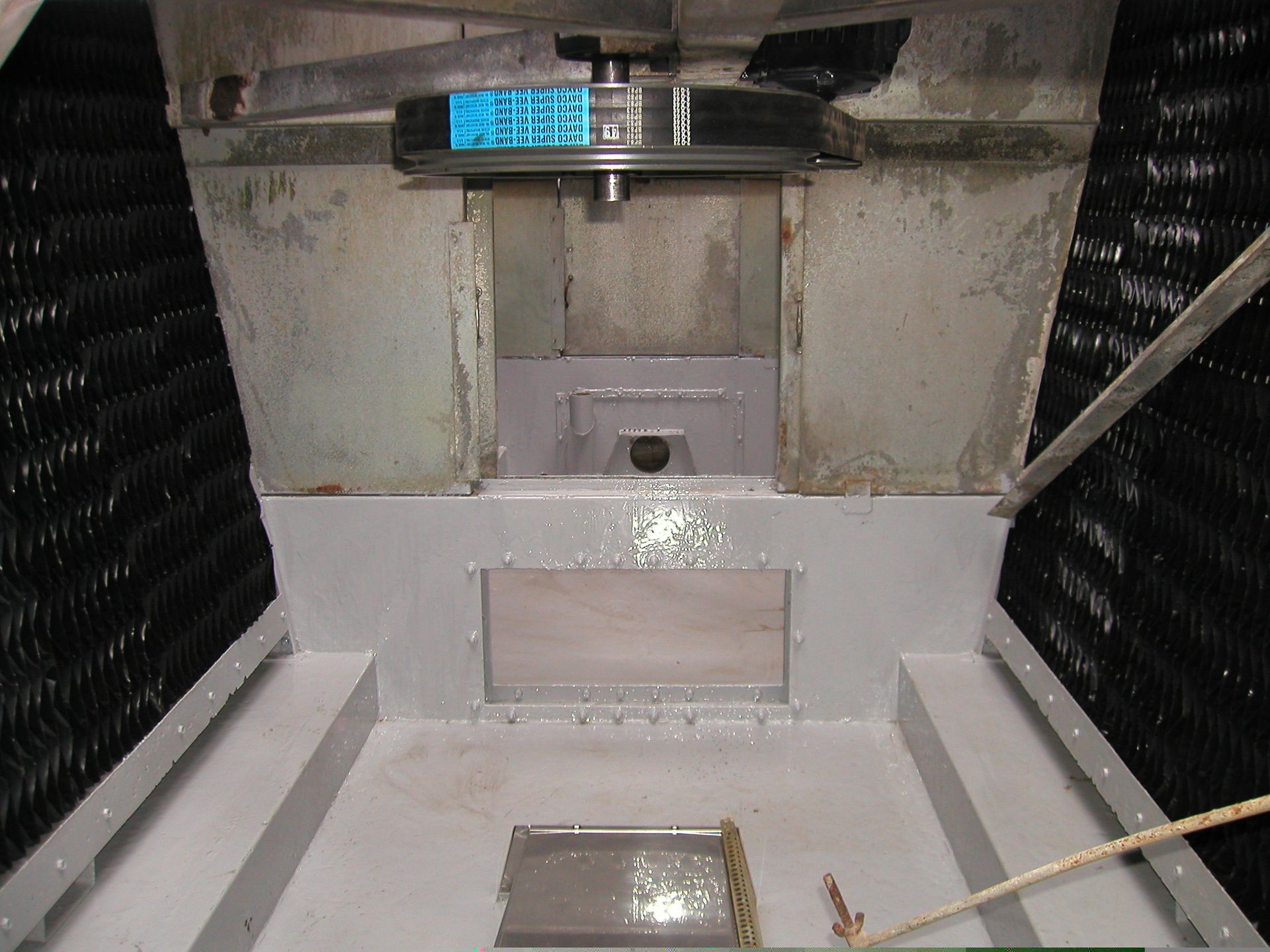 Interior of a small metal chamber with gray walls, vents, and a blue sign near the top.