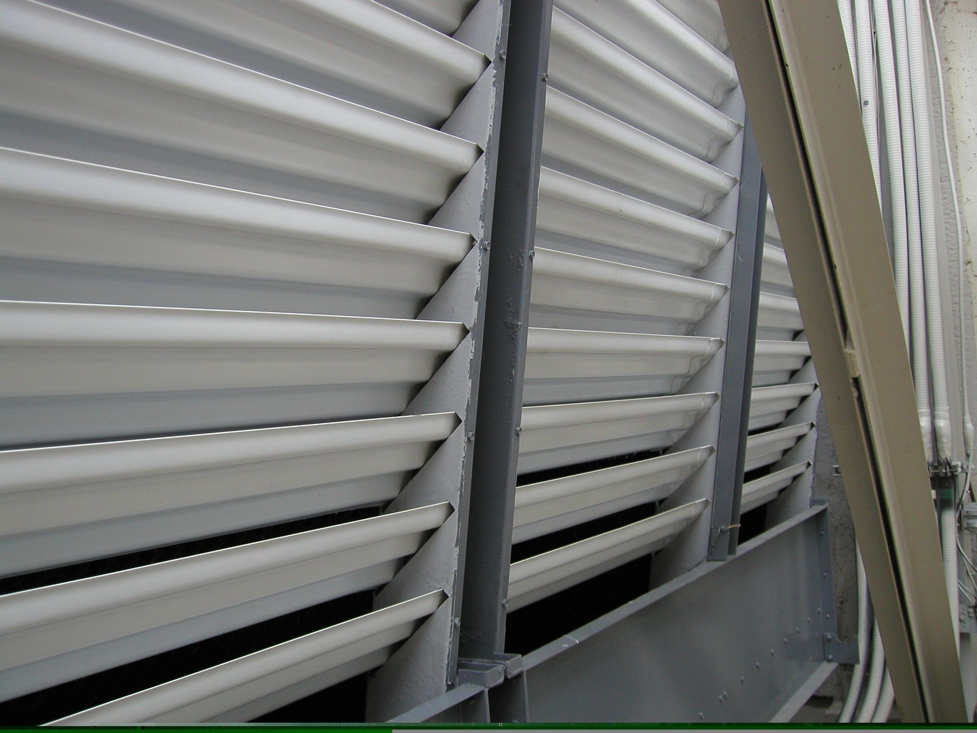 Close-up of gray metal louvers on a building exterior, angled diagonally.