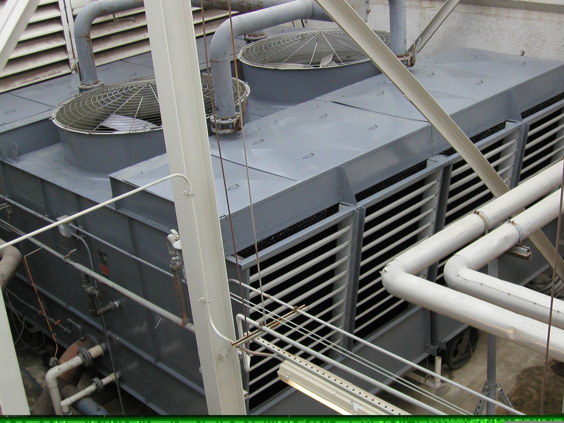 Large gray HVAC unit with ducts and metal railings on a rooftop.