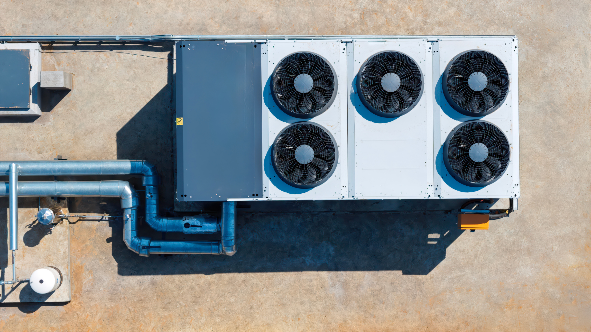 Rooftop HVAC units with blue ducting and six fans on a flat tan roof.
