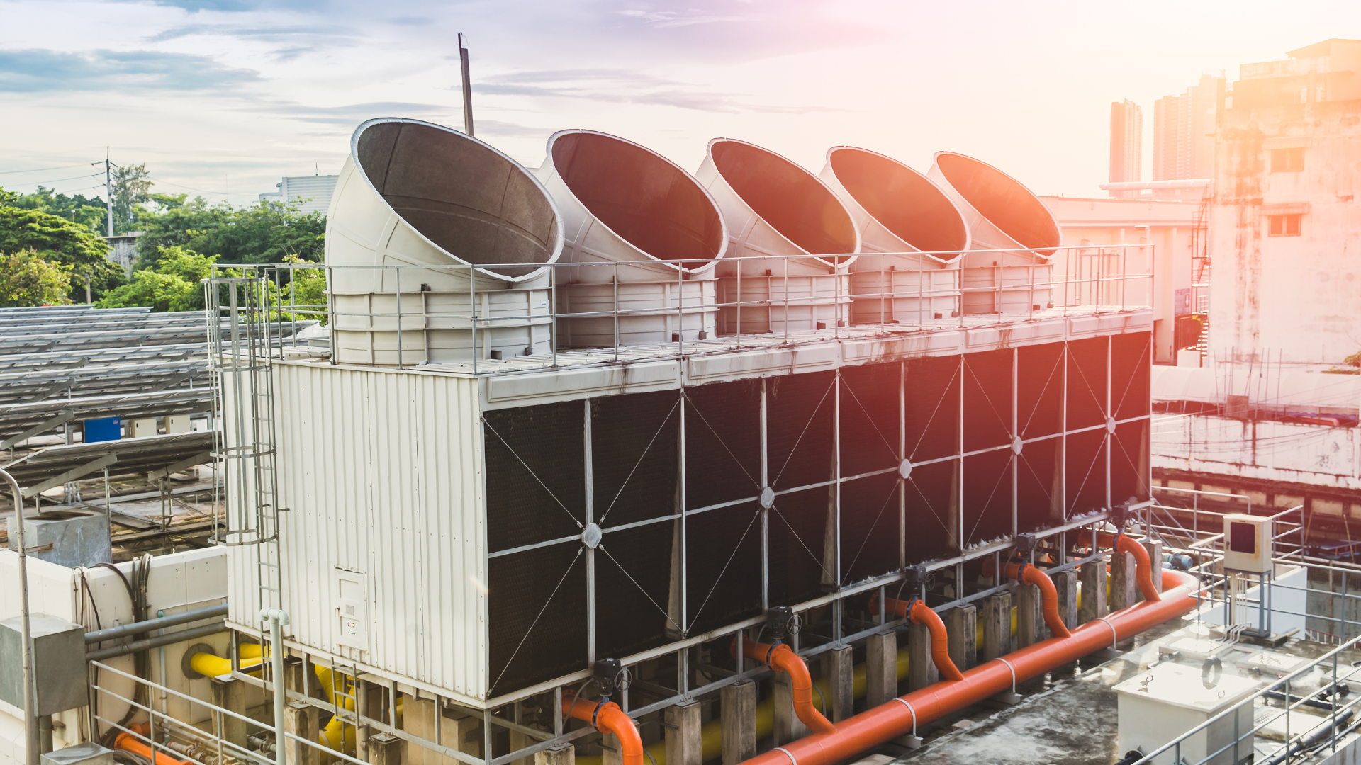 Rooftop HVAC cooling units with large circular fans on an industrial building at sunset