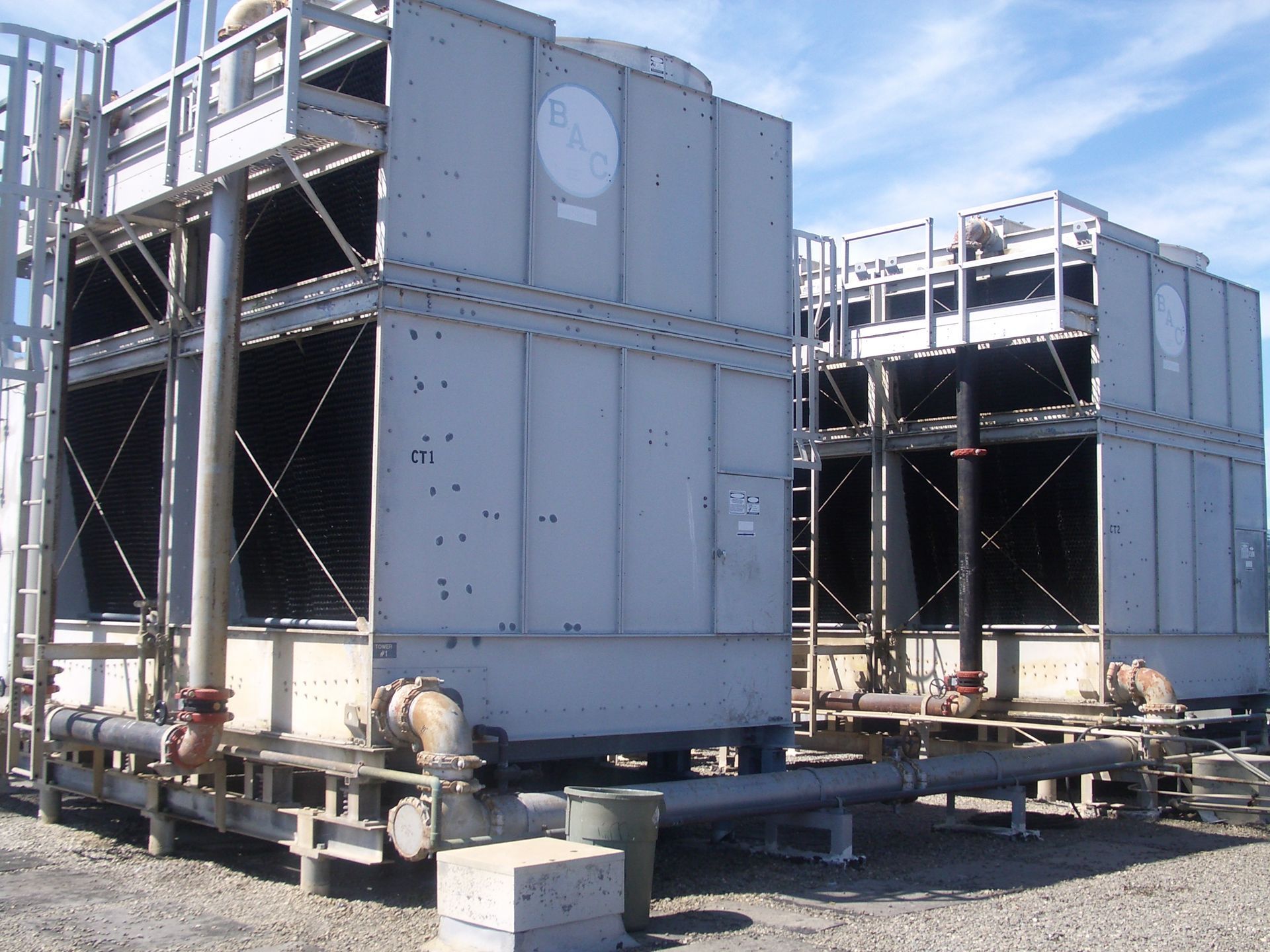 Industrial HVAC units mounted on metal frames outdoors, with ducts and piping visible