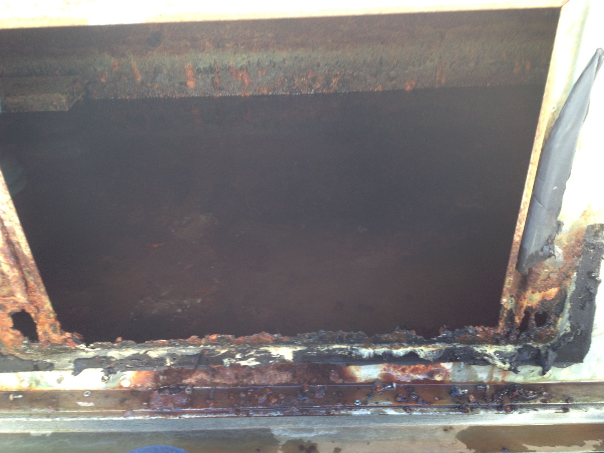 Rusty metal opening with heavy corrosion and peeling paint around the edges