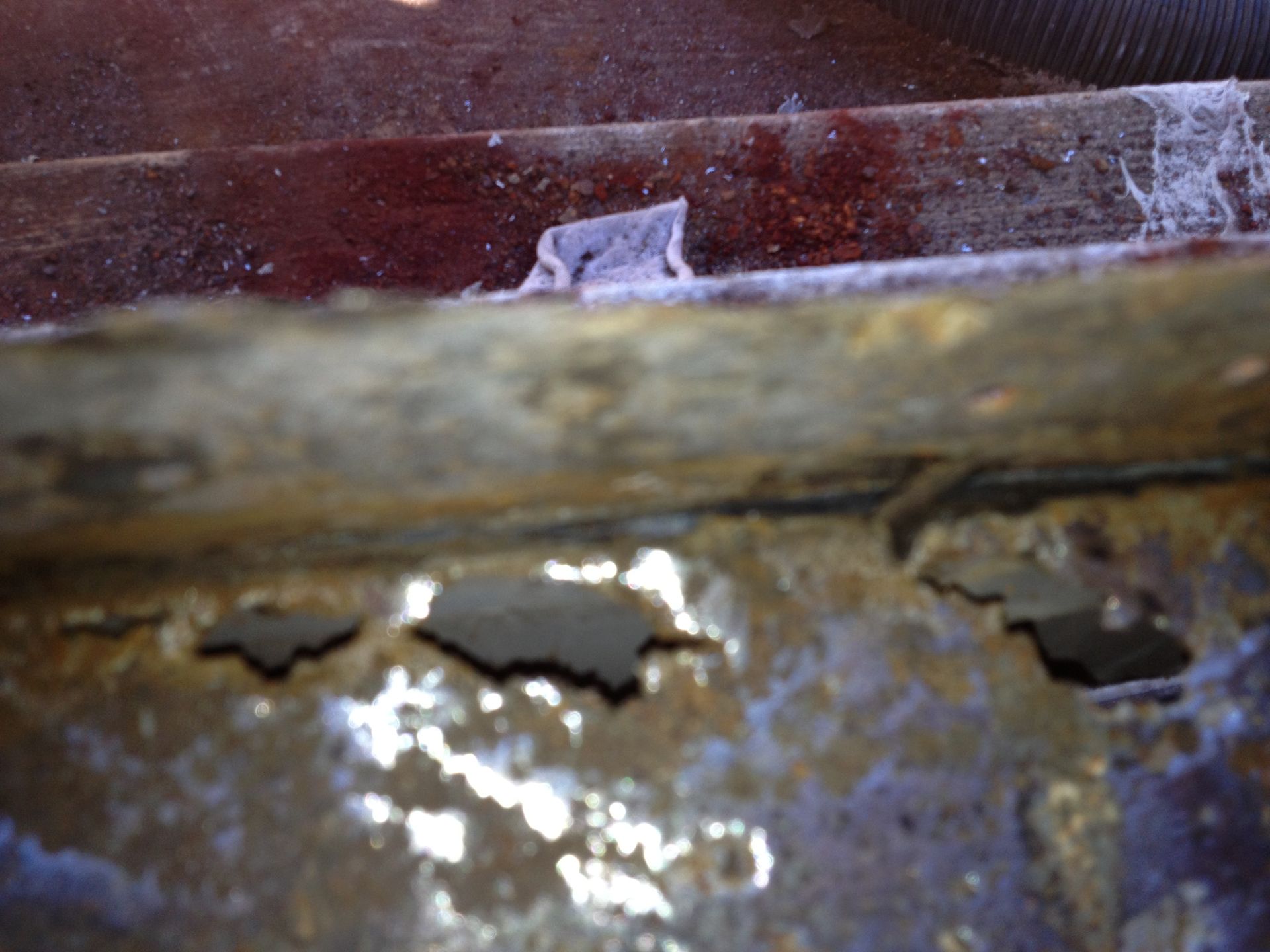 Close-up of a rusty, corroded metal surface with peeling paint and holes.