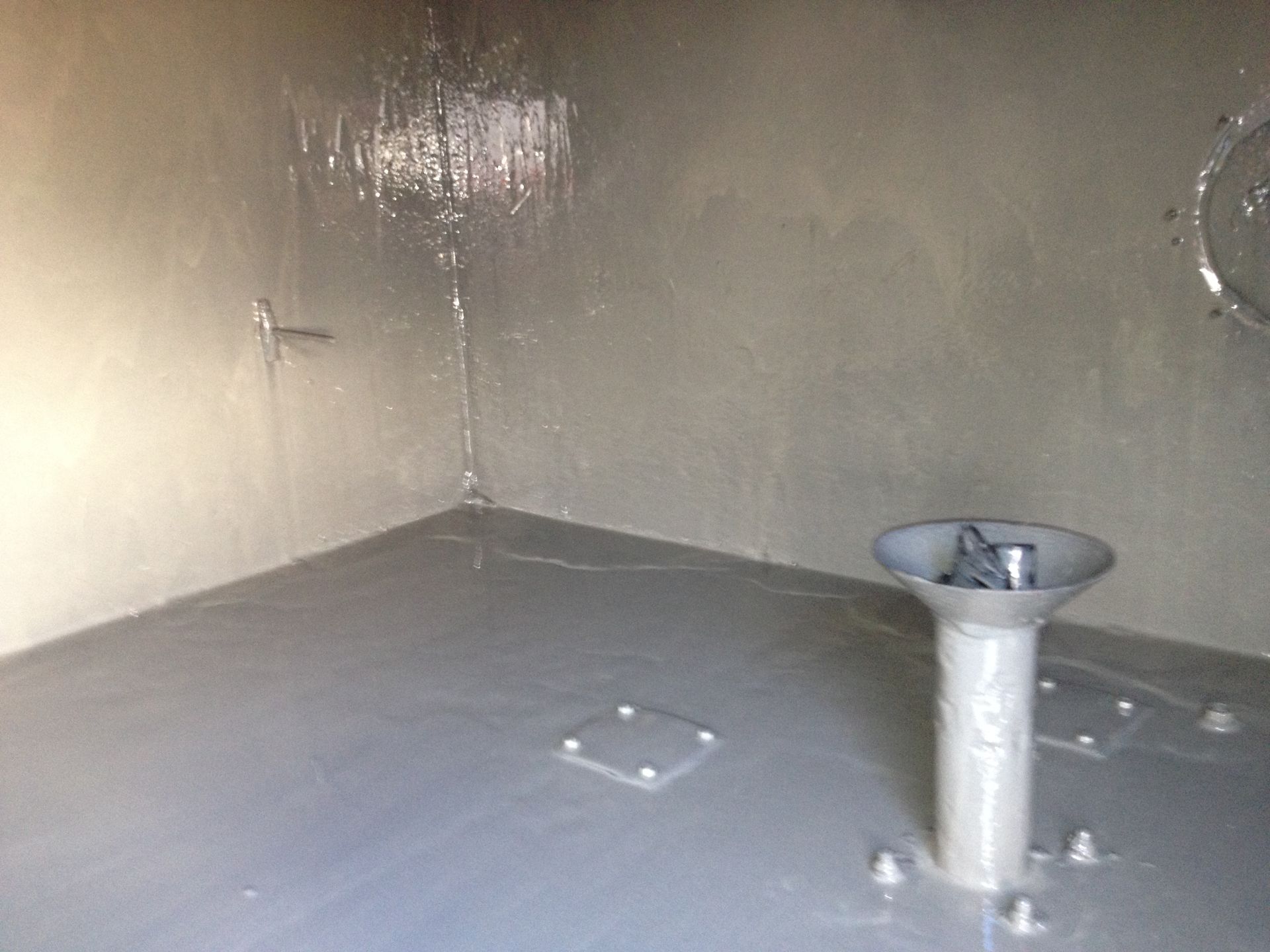 Empty gray utility room with a floor drain and a metal pedestal sink on the right.