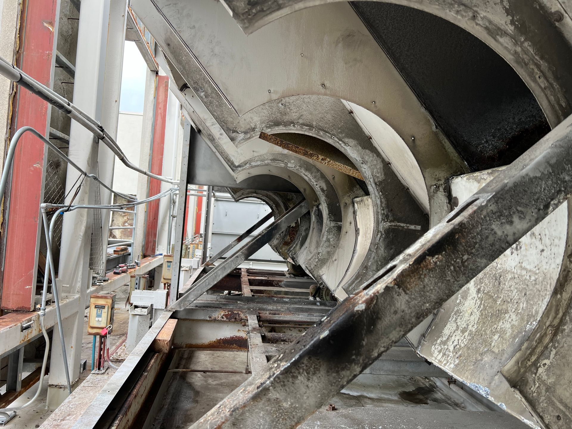 Industrial tunnel interior with concrete arches, scaffolding, and a rail or walkway along the left side