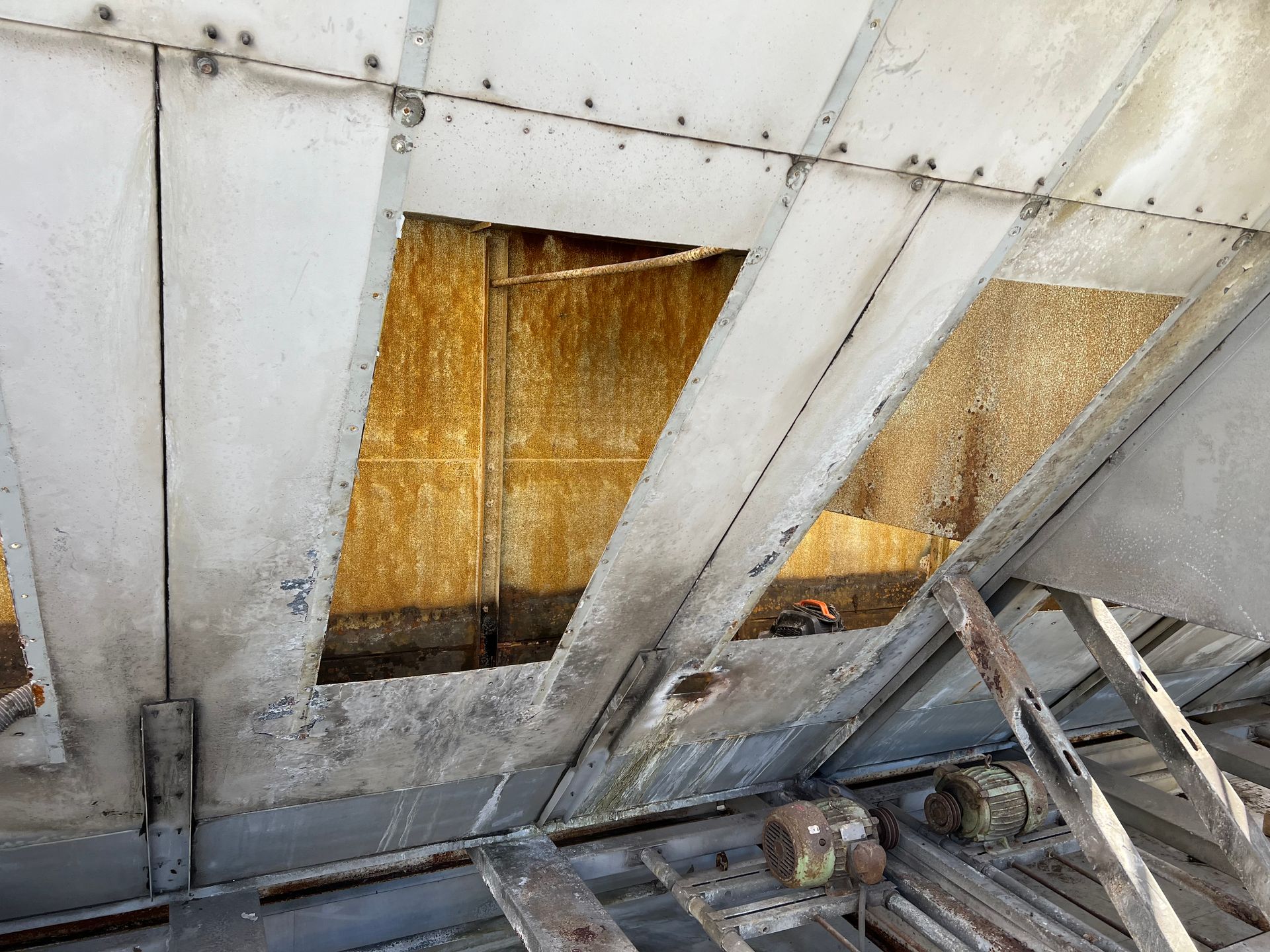 Damaged metal ceiling with rusted panels and a jagged opening exposing insulation