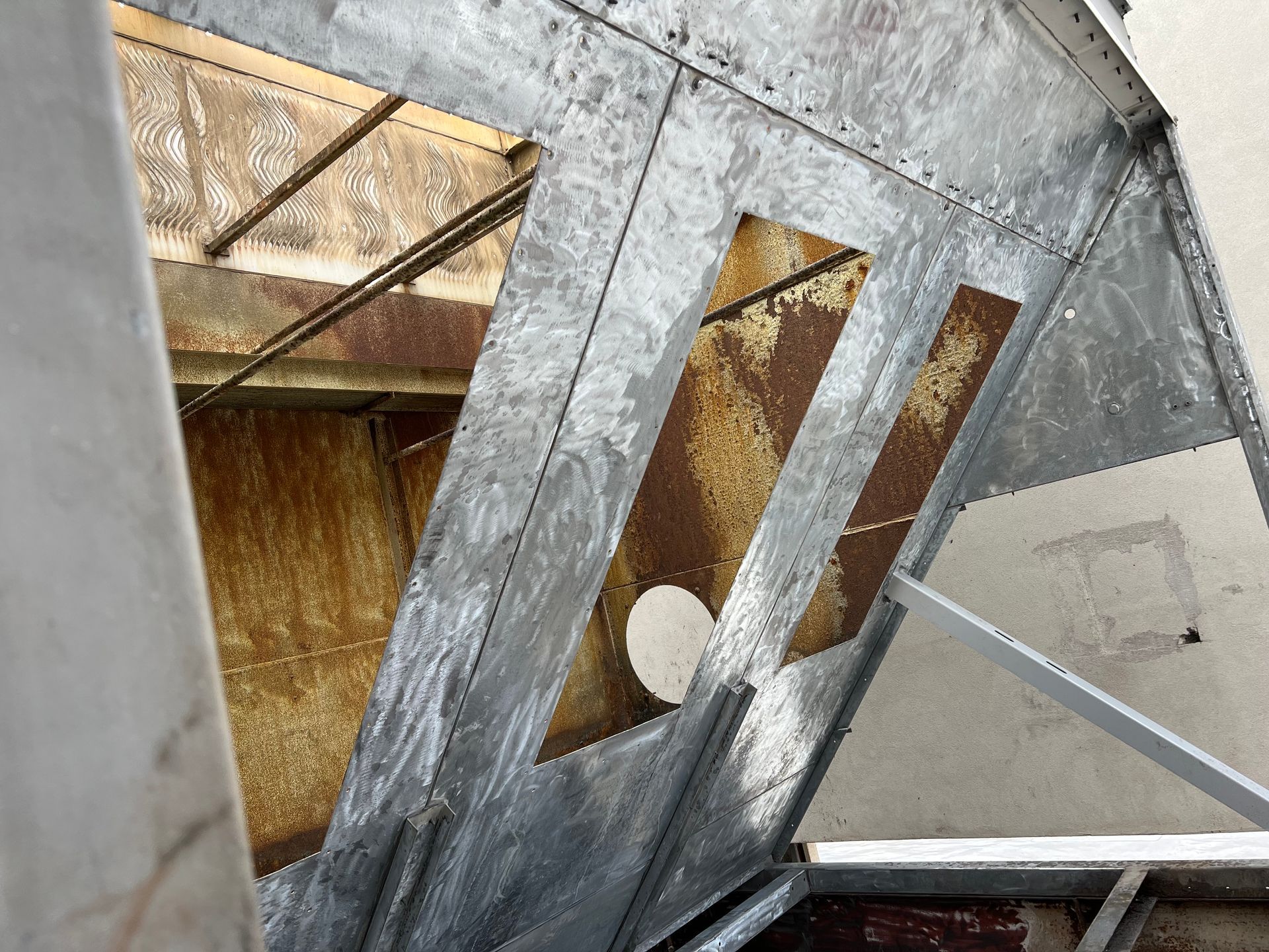 Close-up of a damaged metal structure with torn panels and exposed insulation inside an industrial setting
