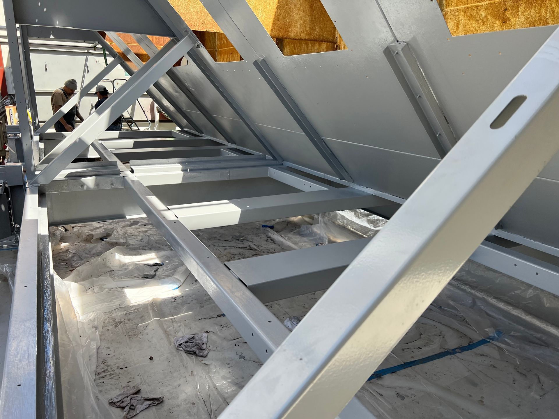 Metal roof framing with diagonal steel beams and insulation panels in a construction area