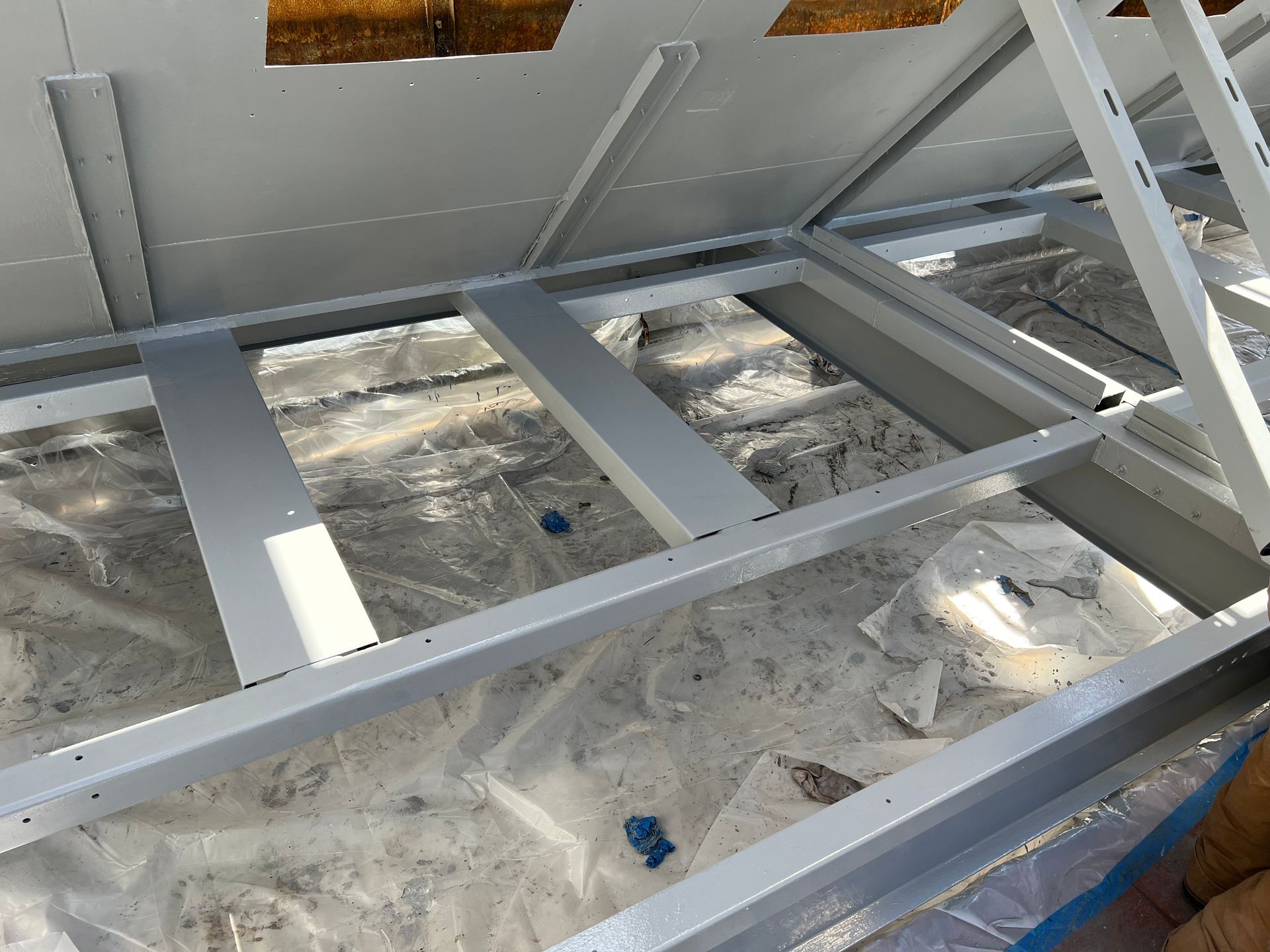 Silver metal frame laid on a concrete floor, with blue tape and debris in a construction site.