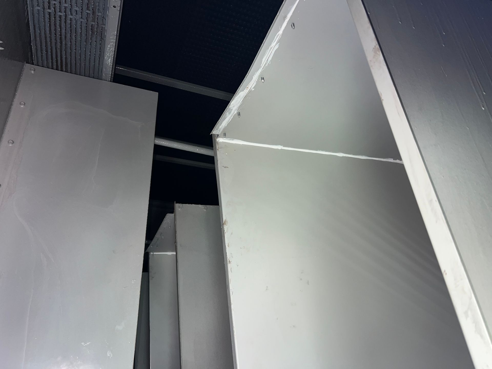 Gray industrial panels and beams inside a dim ceiling space