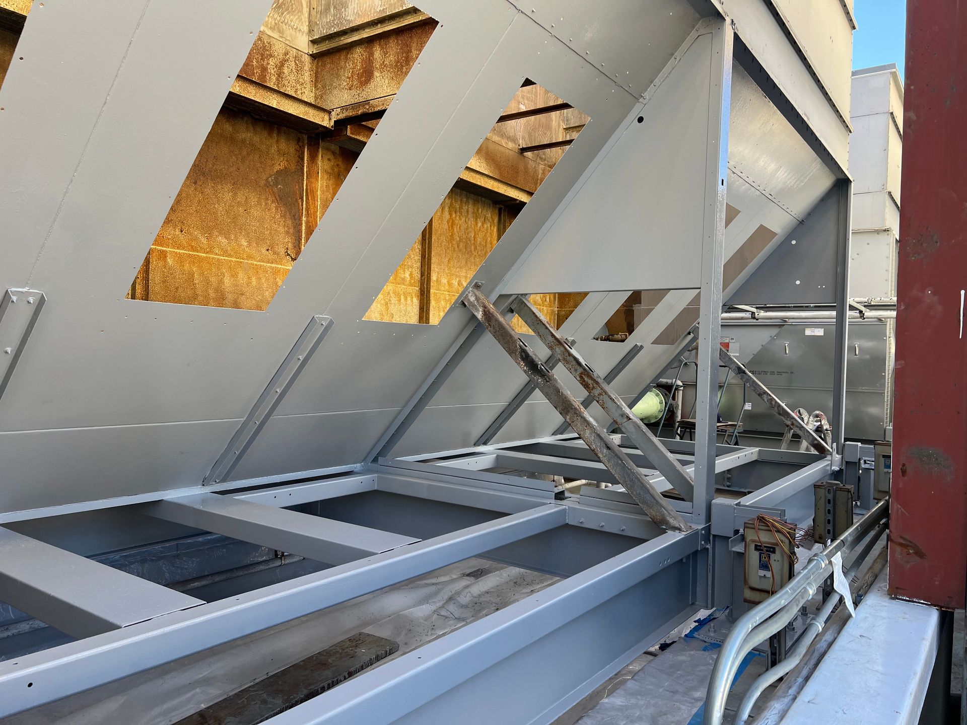 Industrial steel framework with angled gray panels and exposed metal beams in a construction setting