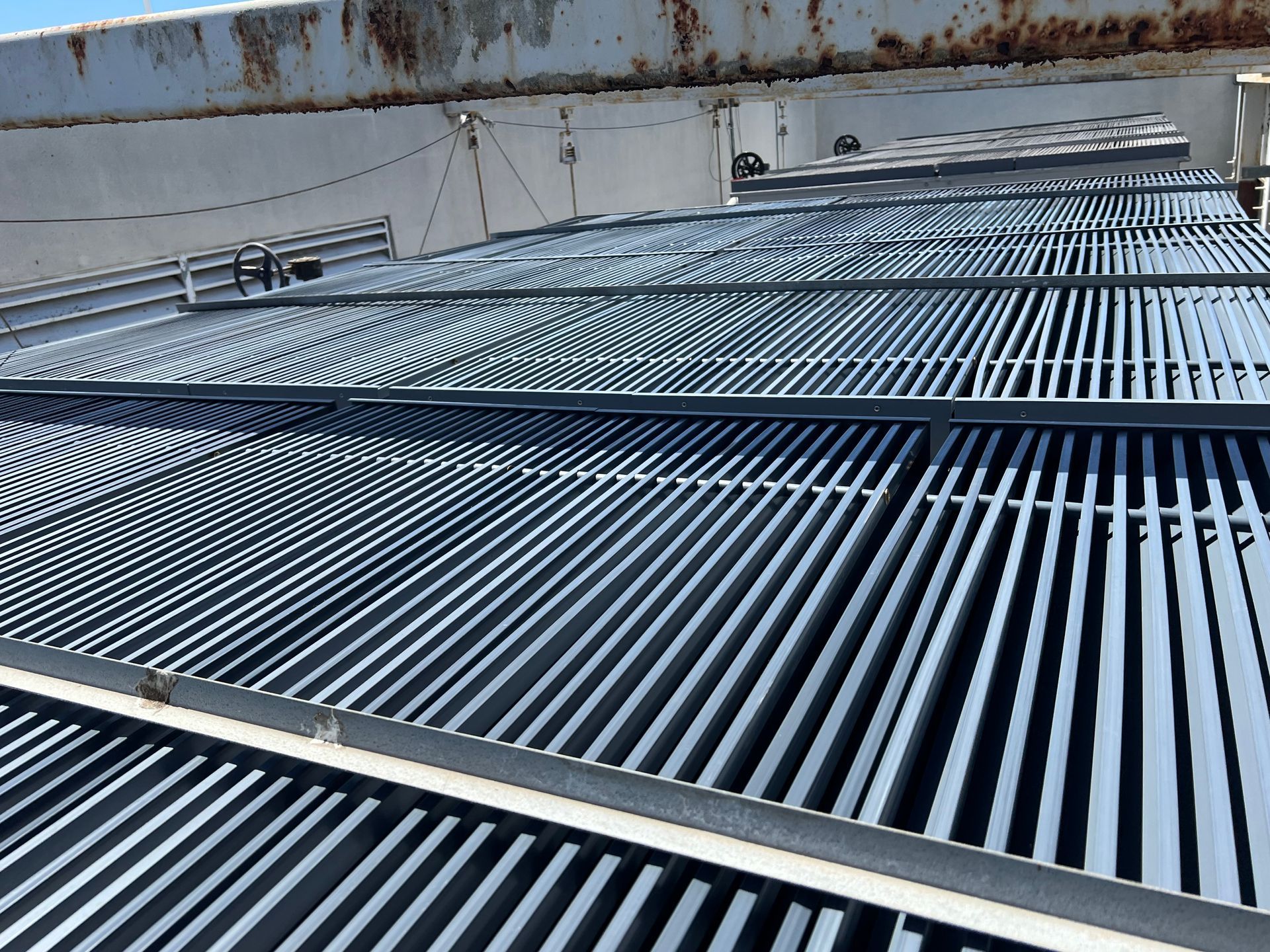 Rows of blue-gray metal rooftop vents and grates against a weathered wall