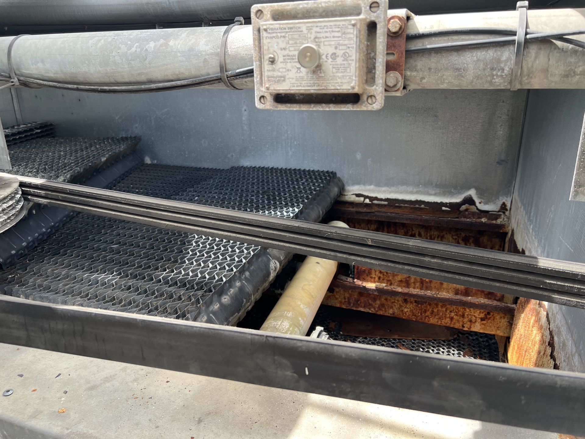 Rusty industrial machinery with pipes and metal grates inside a concrete pit