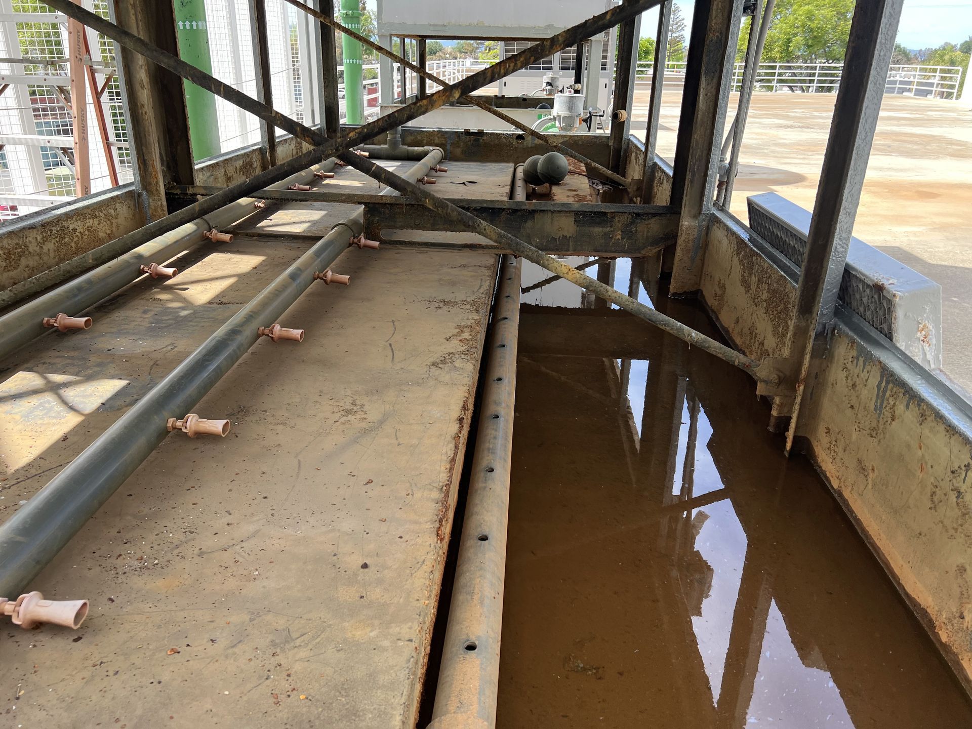 Scaffolding walkway with muddy standing water and construction debris, viewed from inside a building frame