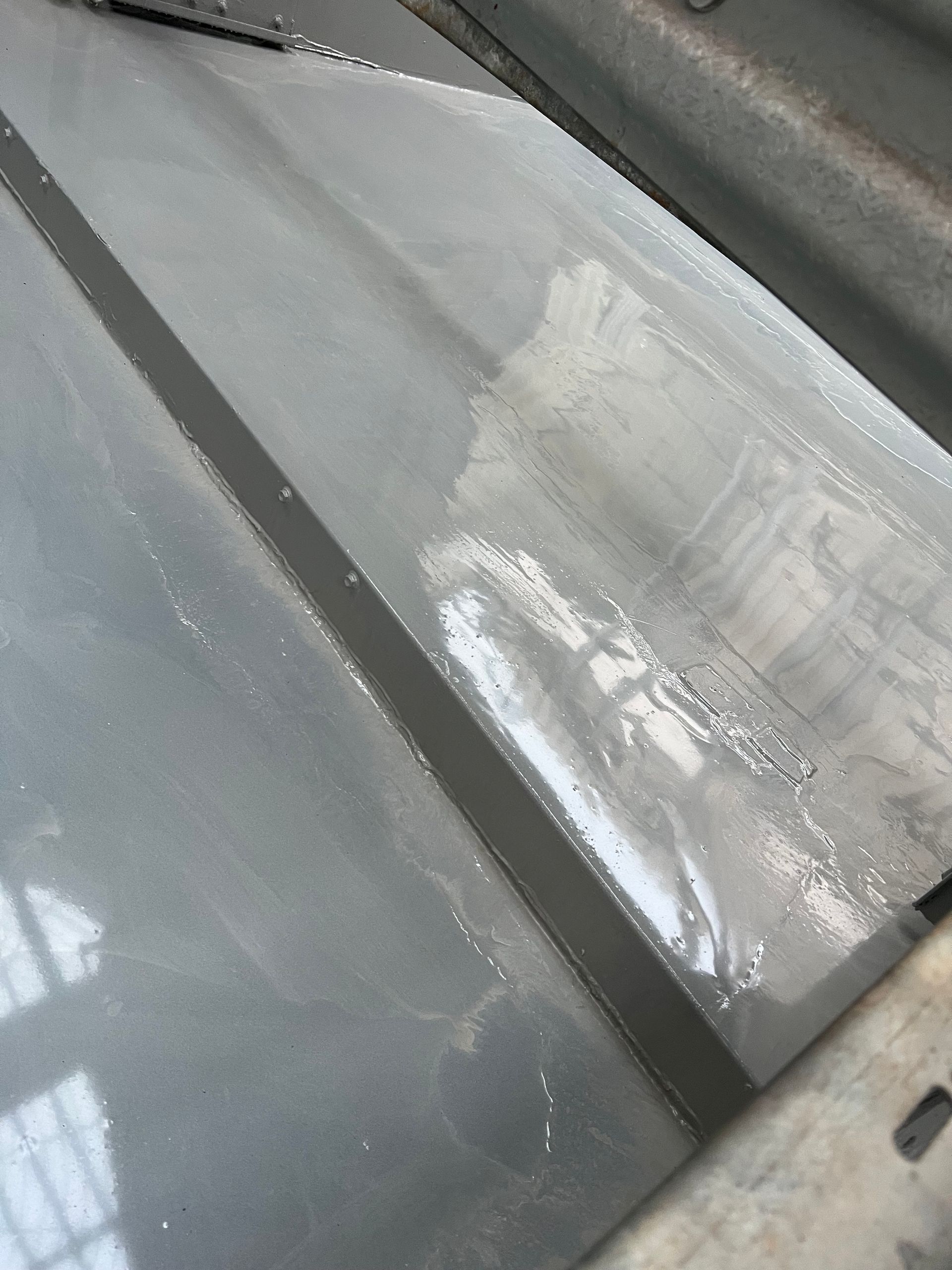 Close-up of a gray car windshield with a white scraped or damaged patch near the center.