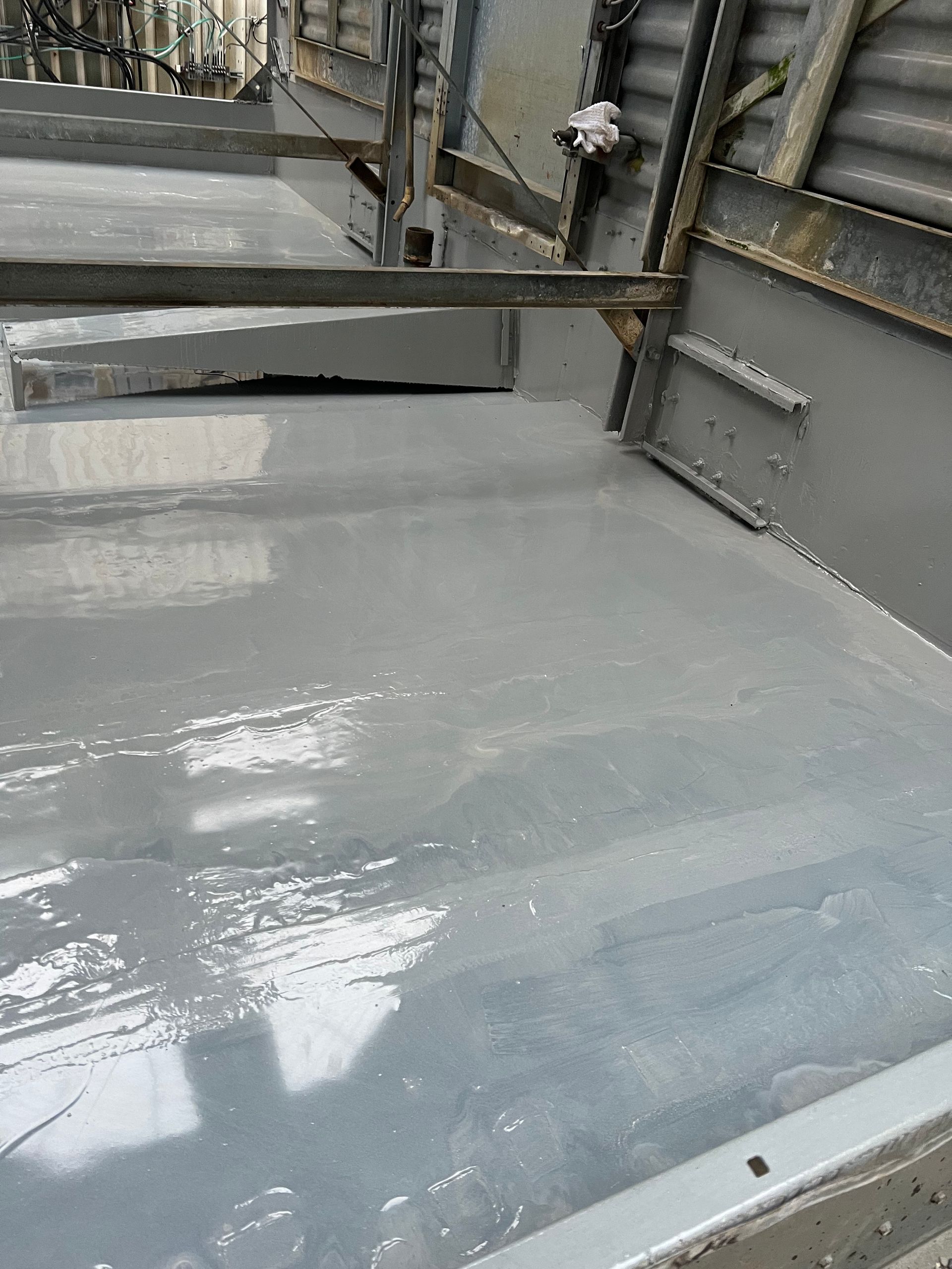 Wet gray industrial floor with a metal railing and stairs along the side.