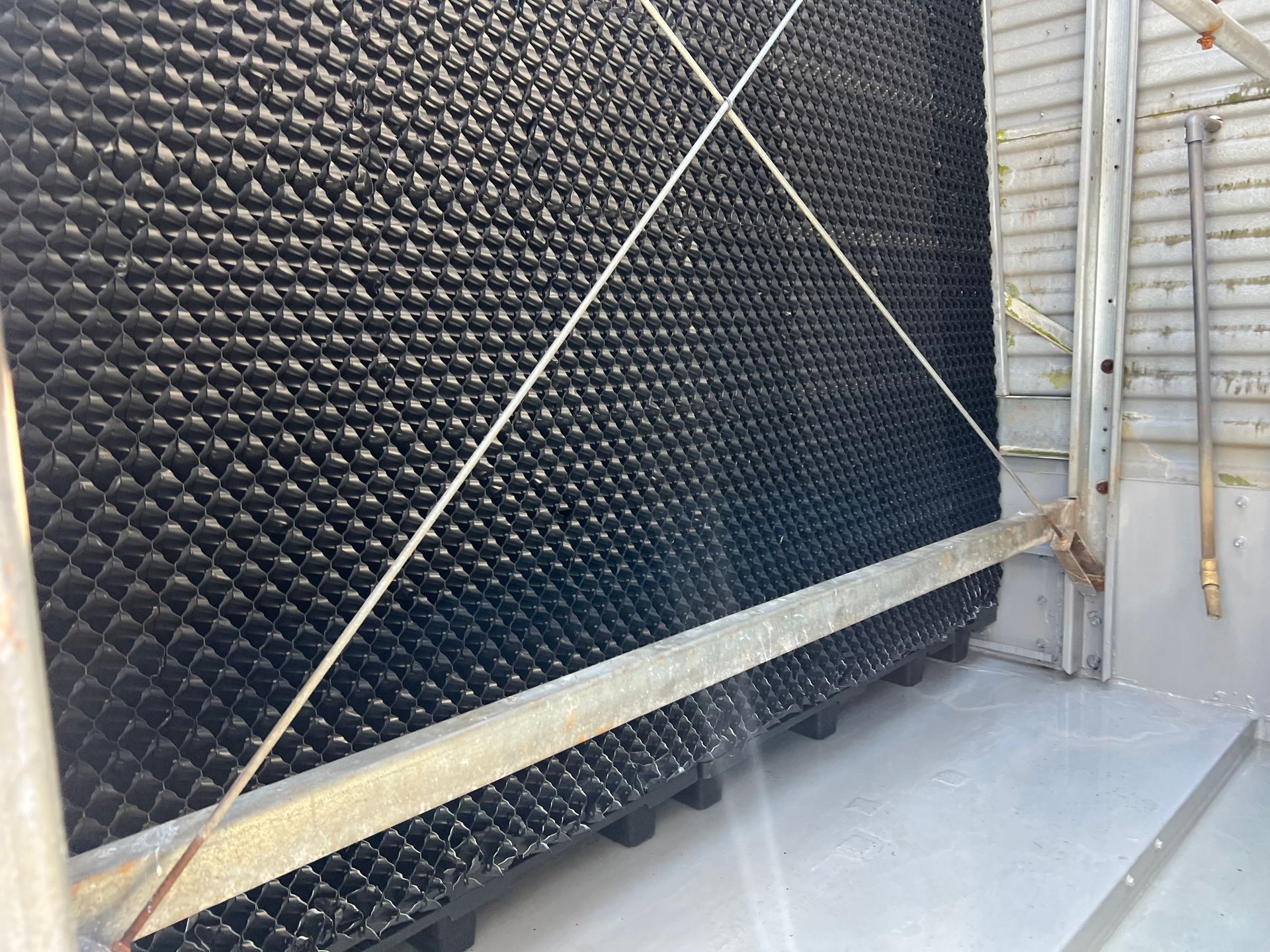 Black padded wall with diagonal braces beside a metal staircase in an industrial interior