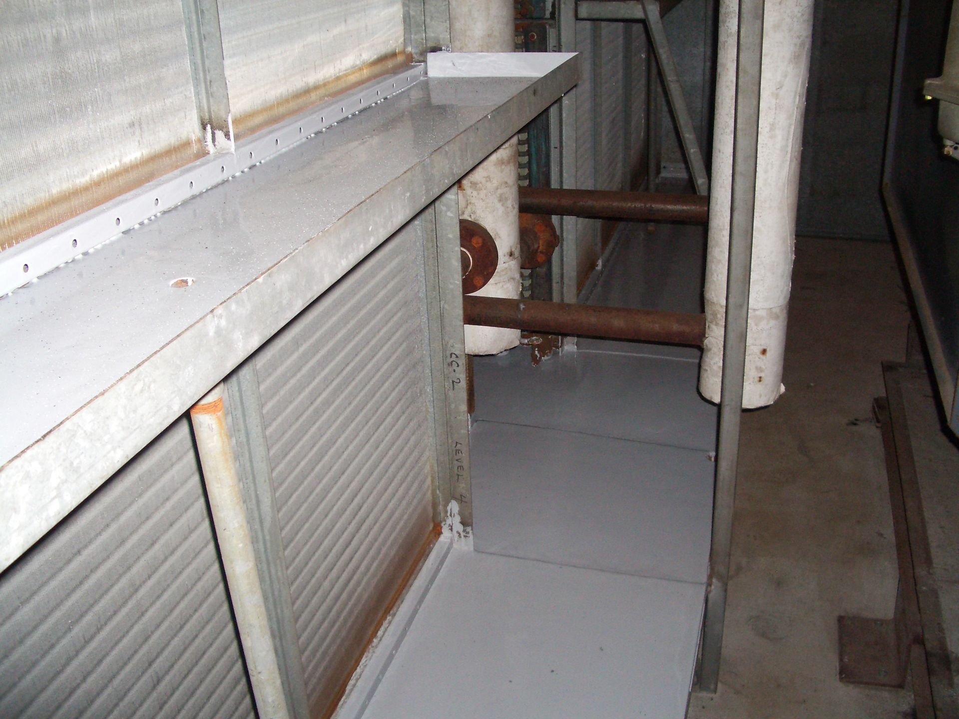 Indoor utility area with white radiator, tiled floor, and exposed pipes along a wall