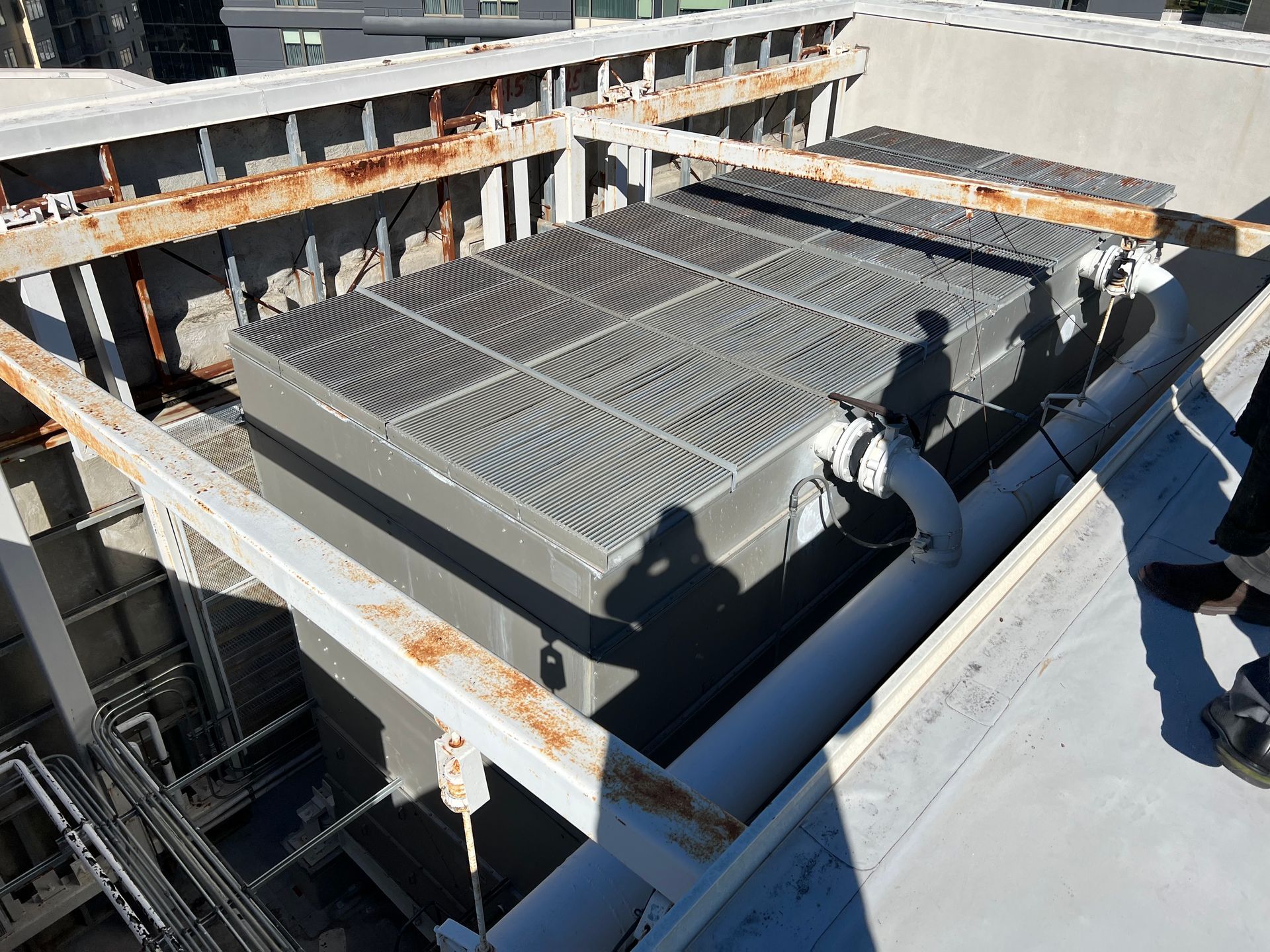Rooftop HVAC unit being installed on a building, with workers' shadows on the deck.