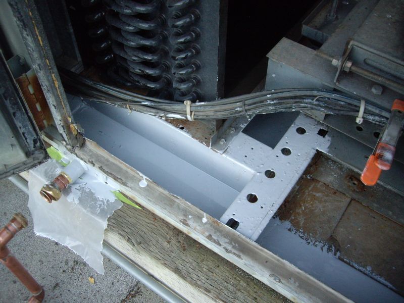 Open machine interior showing a metal trough, wires, and copper pipes, possibly for plumbing or refrigeration.
