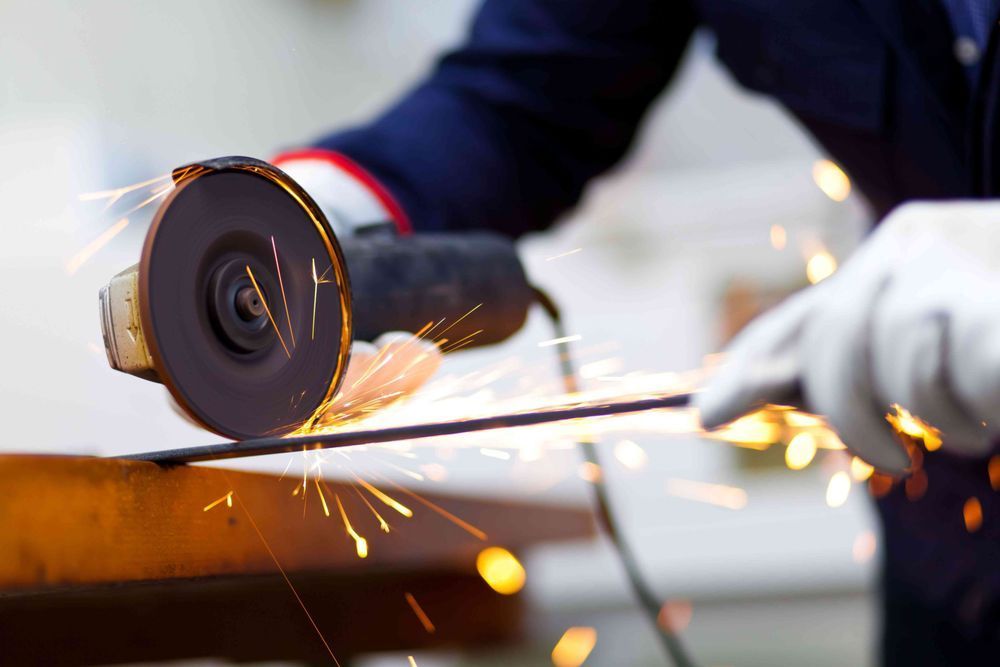 A person is cutting a piece of metal with a grinder.