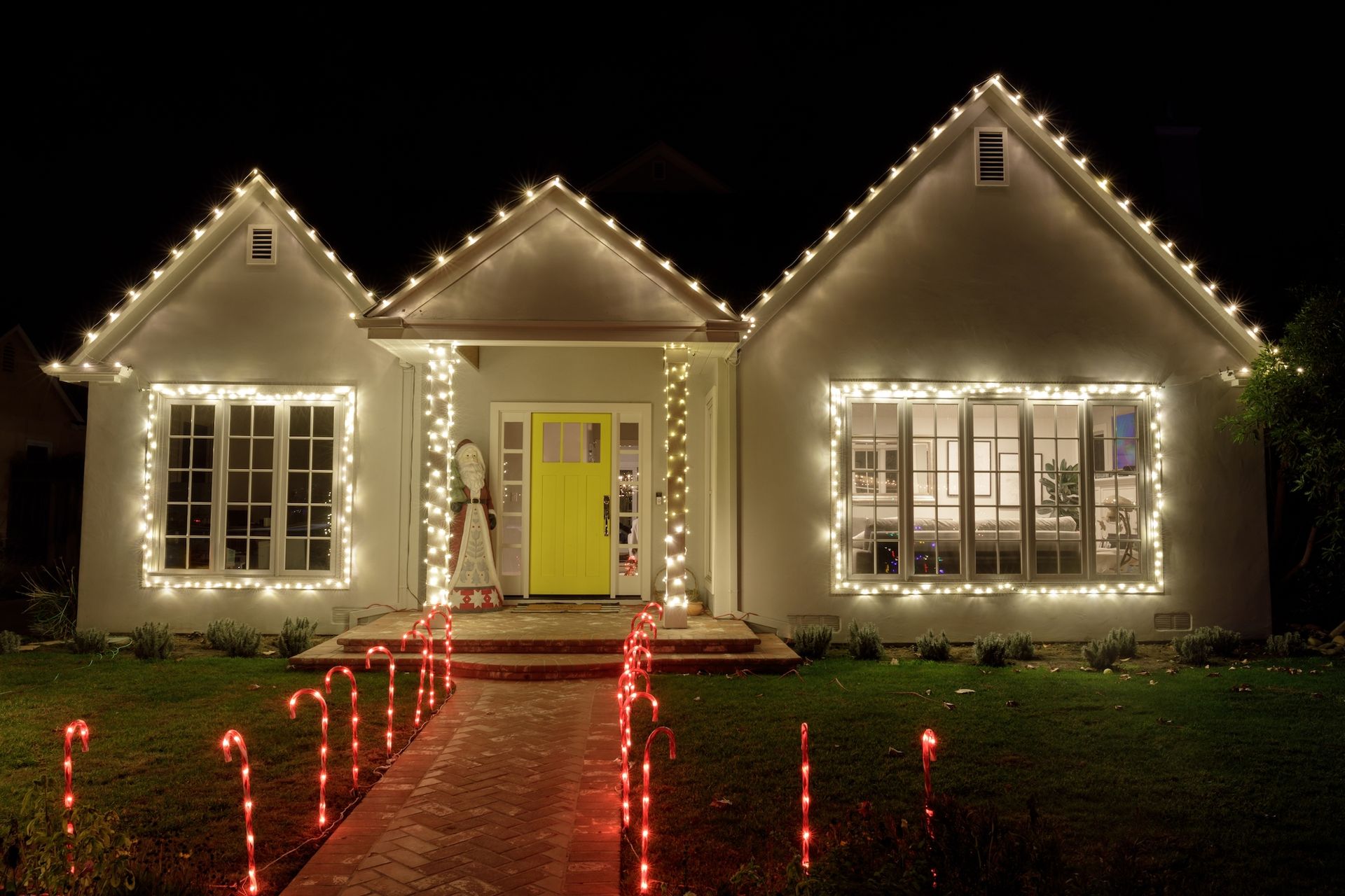House decorated with white Christmas lights and red walkway lights at night