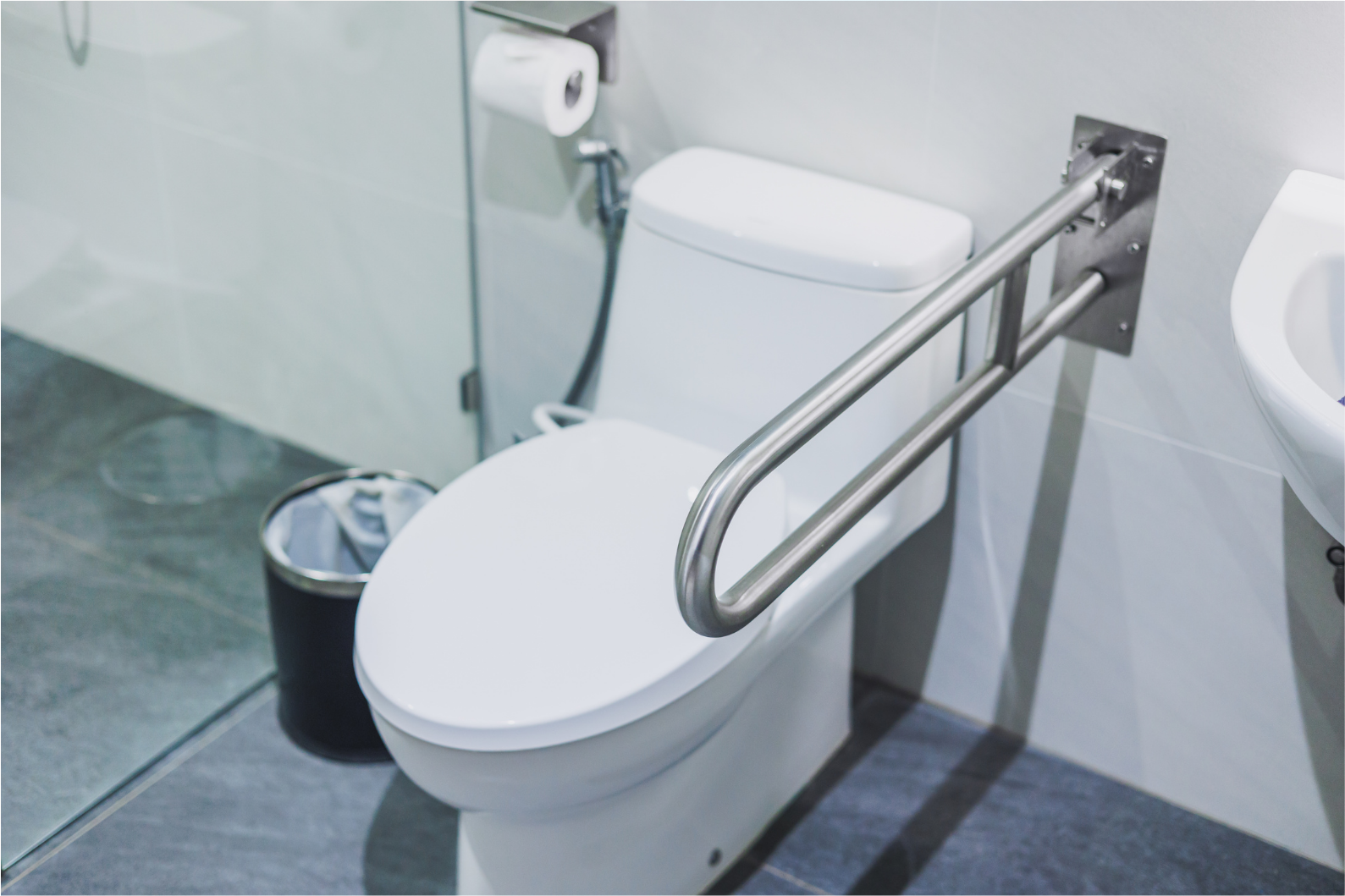 Modern bathroom with a white toilet, featuring a silver grab bar for accessibility.