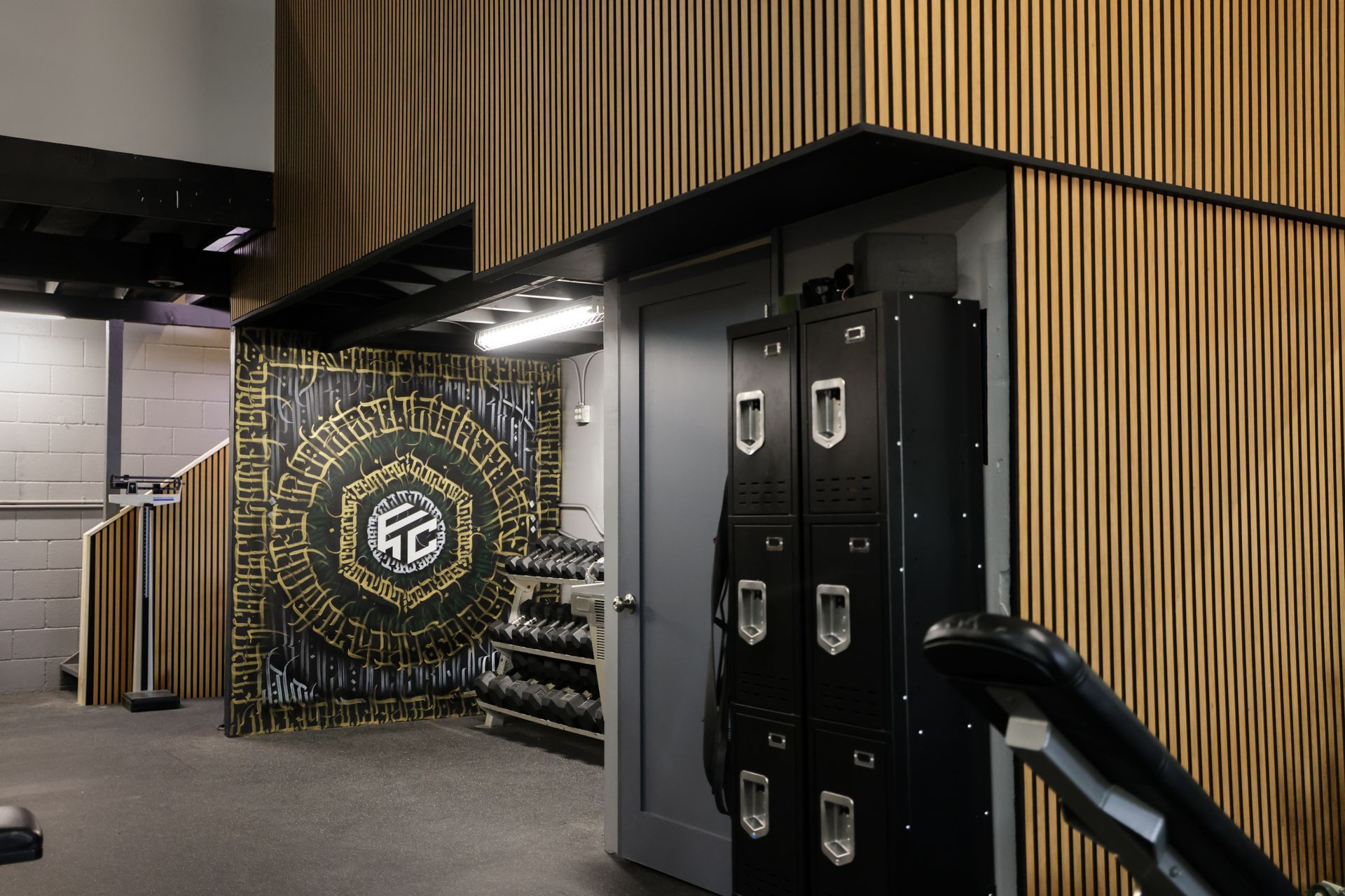 Gym interior with black lockers, wooden paneling, and a mural.