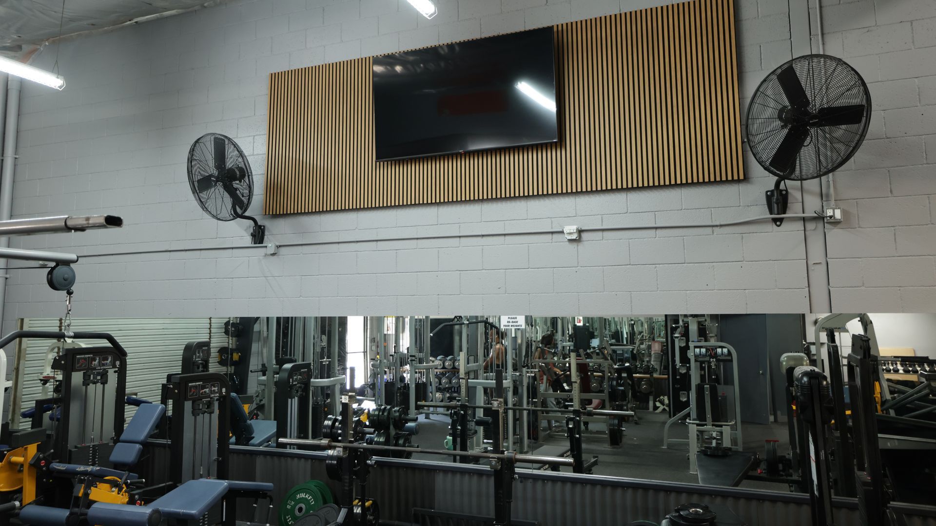 Woman in a gym doing a side lunge with a medicine ball. The gym is bright and has weight equipment.