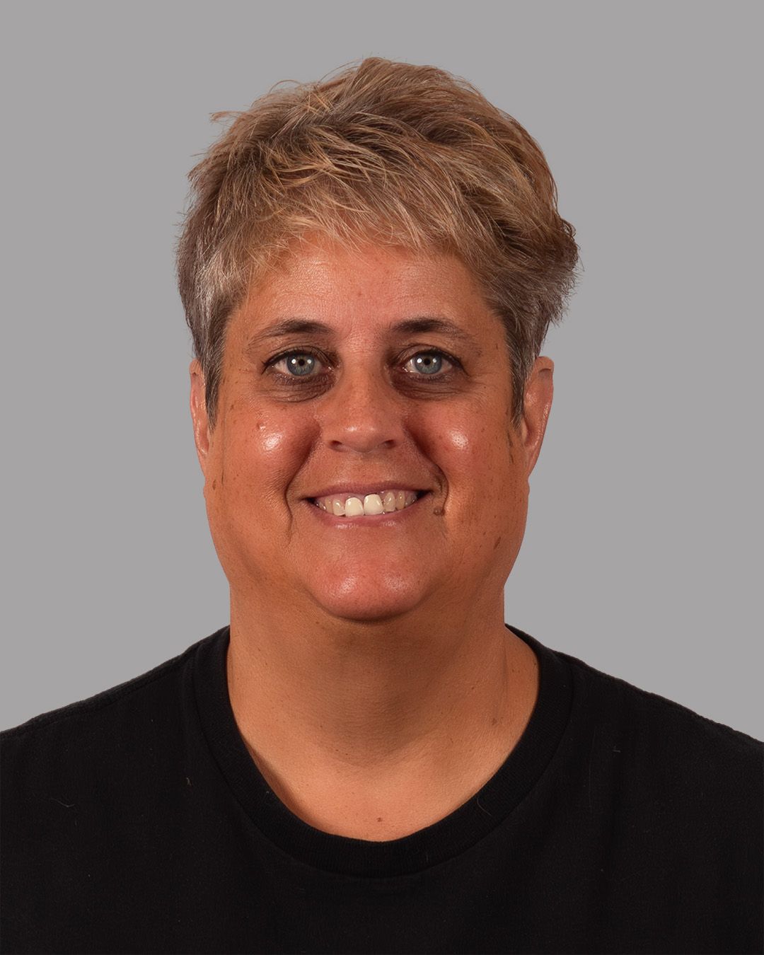 A woman wearing a necklace and earrings is smiling for the camera.