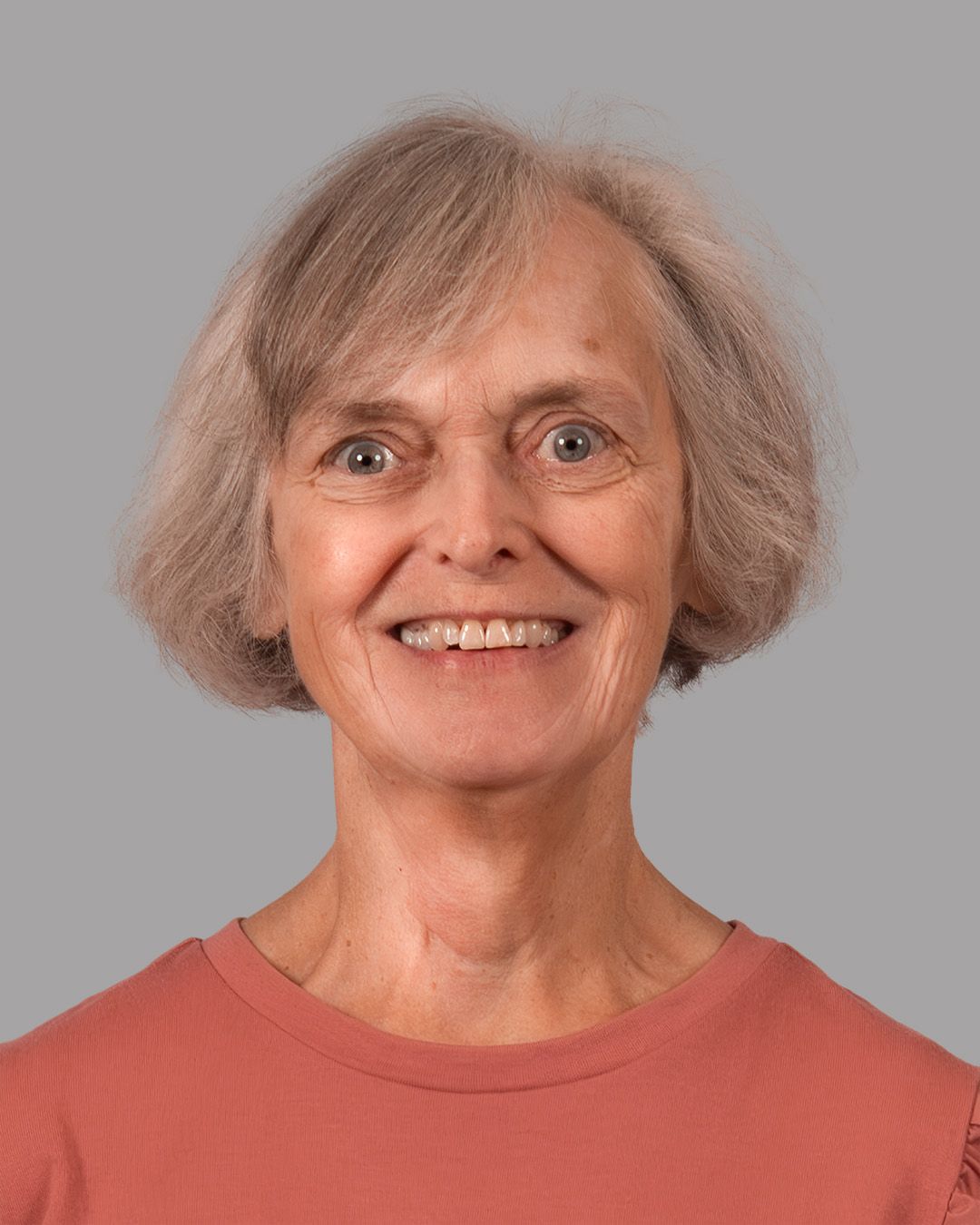 A woman in a pink and black floral dress smiles for the camera