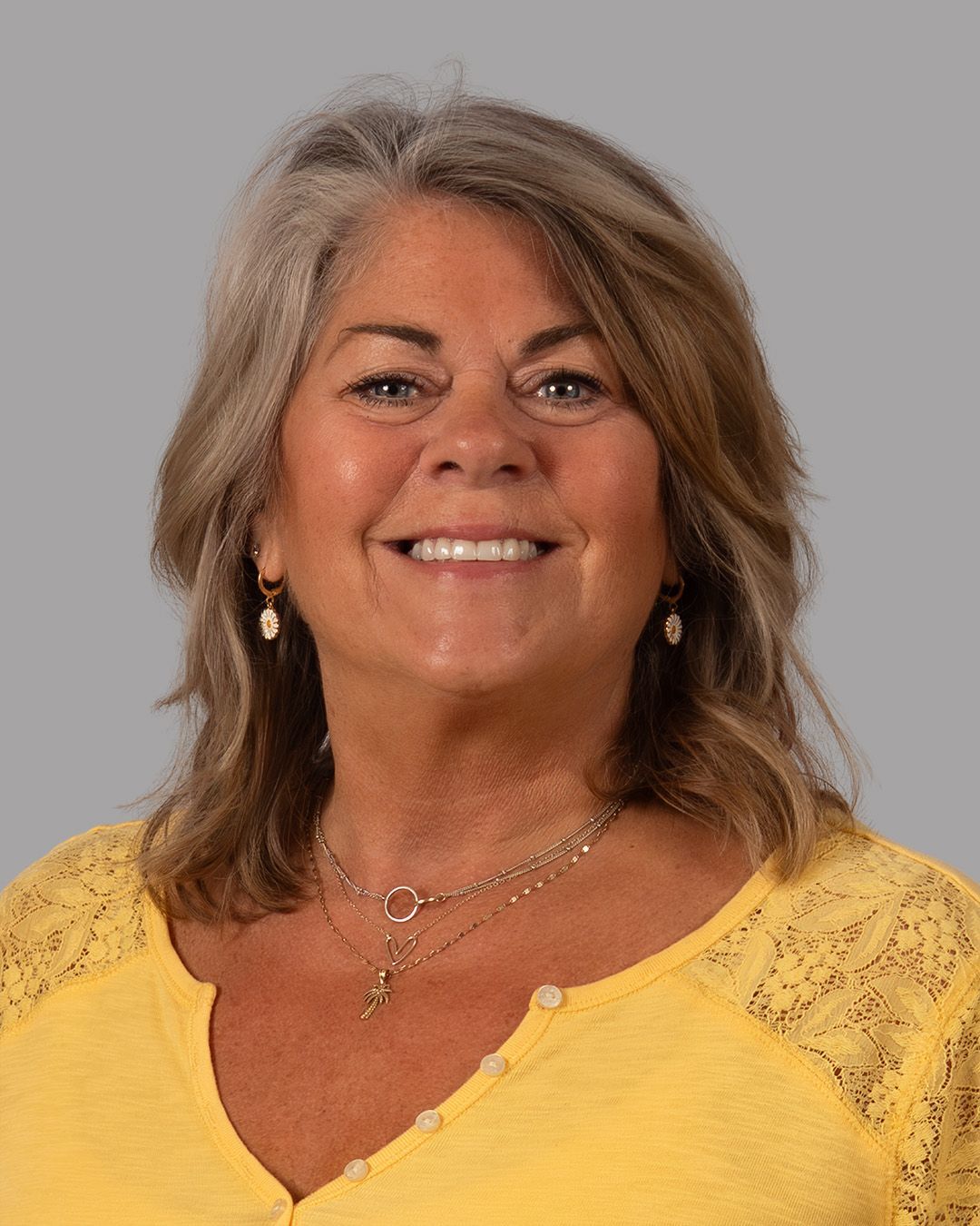 A woman wearing a black shirt and a brown collar is smiling for the camera.