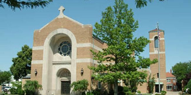 A large brick church with a steeple and a cross on top of it
