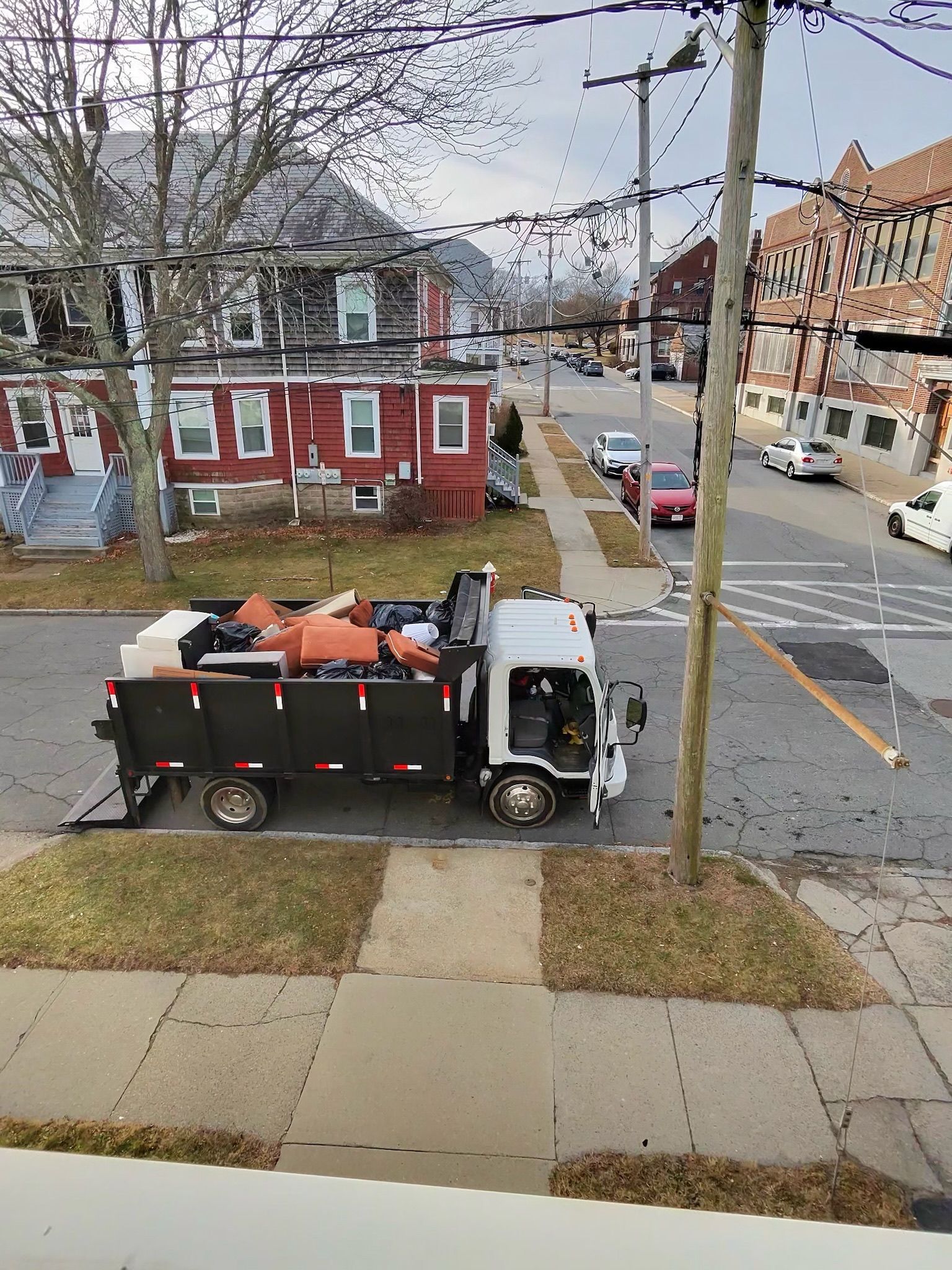 Junk removal crew loading truck in residential driveway