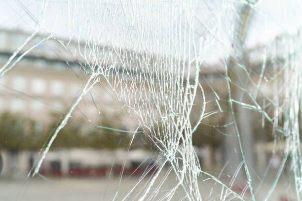 A close up of a broken glass window with a blurry background.