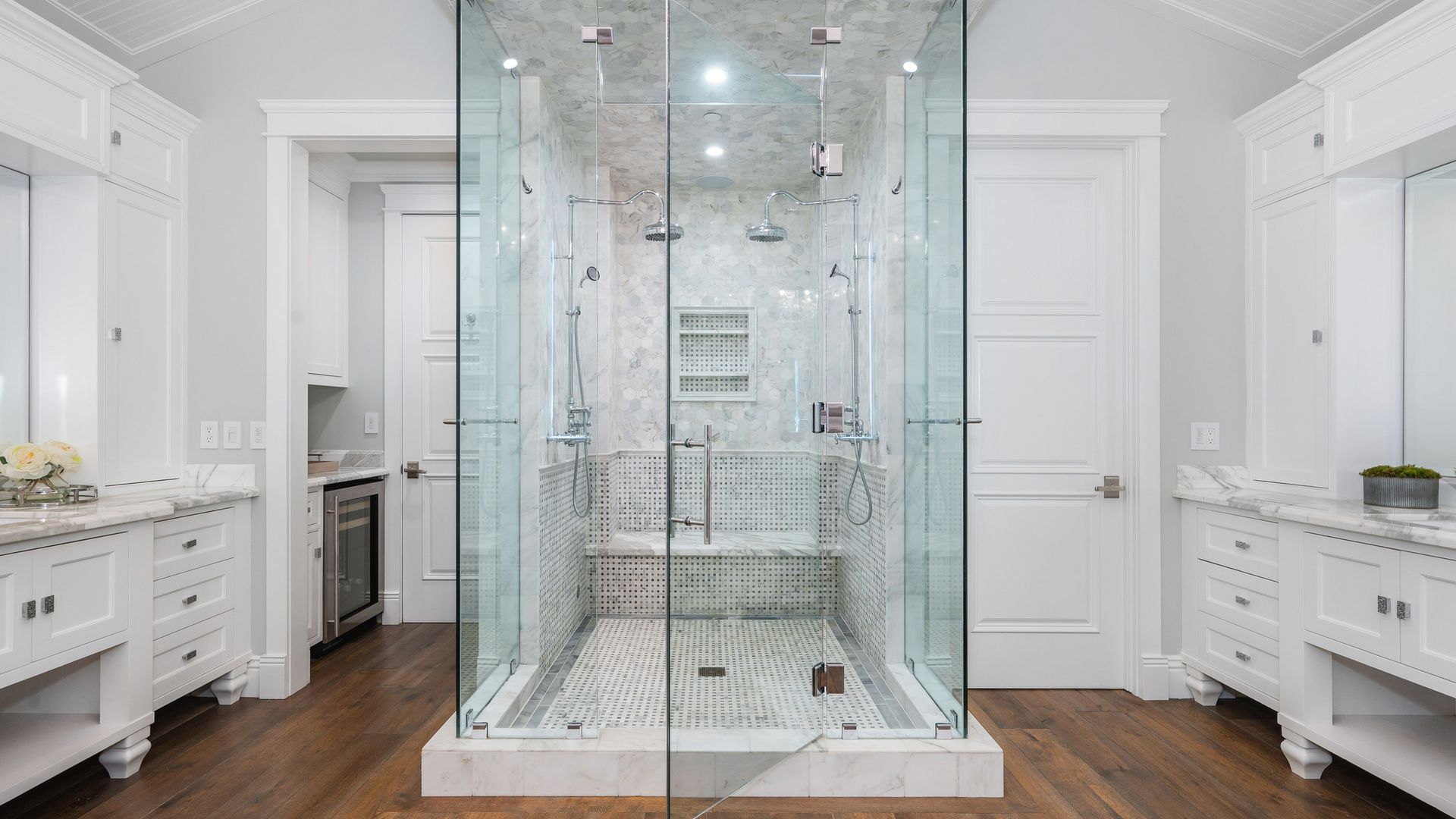A bathroom with a walk in shower and two sinks.