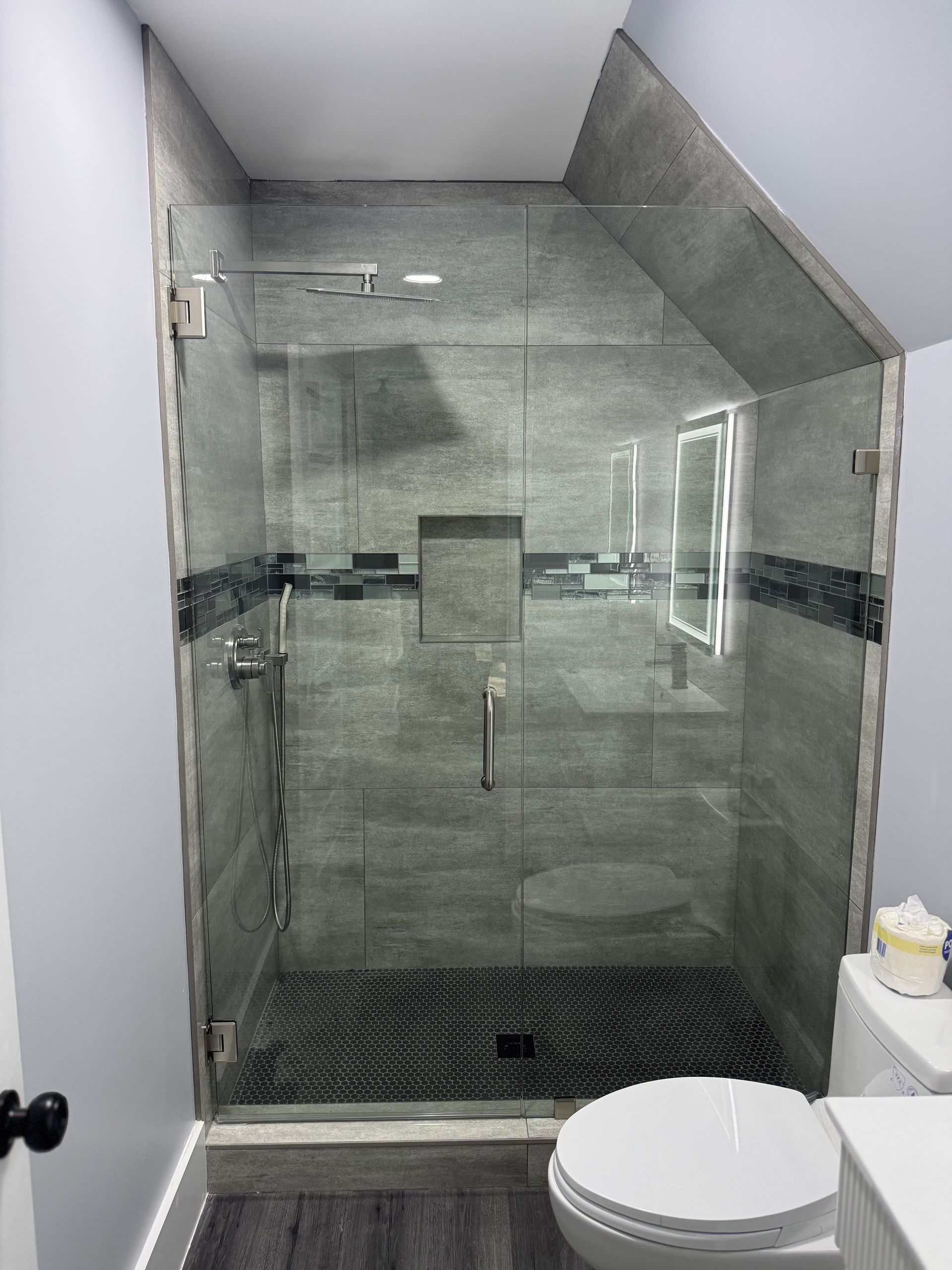 A bathroom with a toilet and a shower with a glass door.