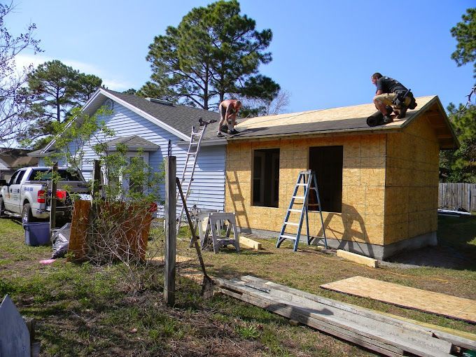 Two men are working on the roof of a small house.