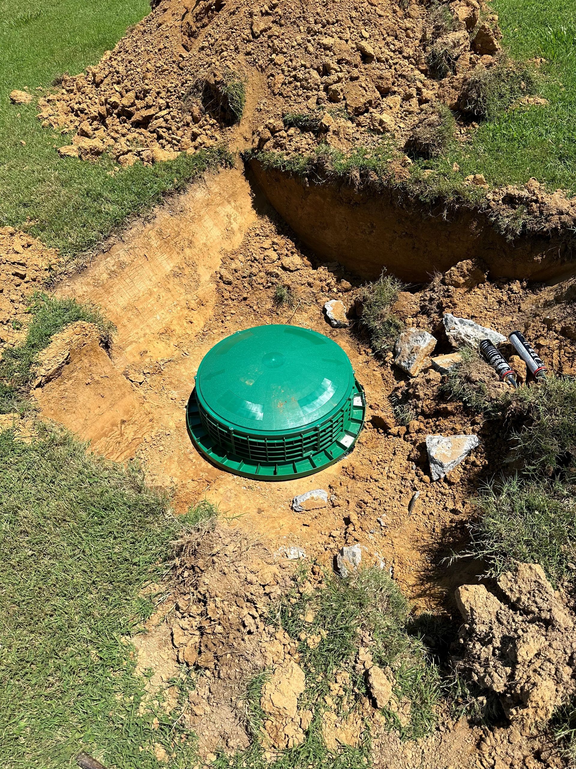 A green container is sitting in the middle of a dirt field.