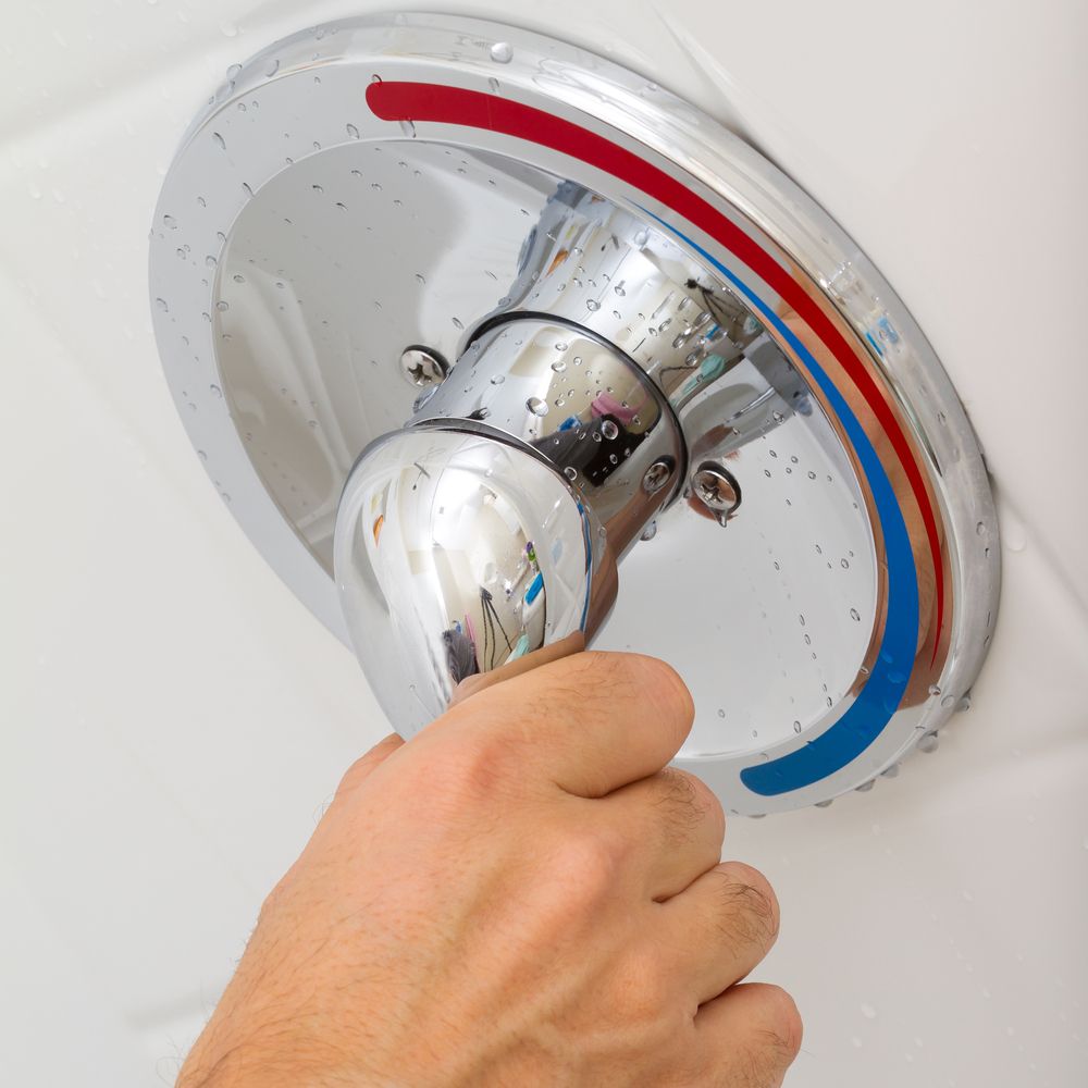 A Person Is Adjusting A Shower Head With A Red And Blue Handle — DMK Plumbing in Port Macquarie, NSW